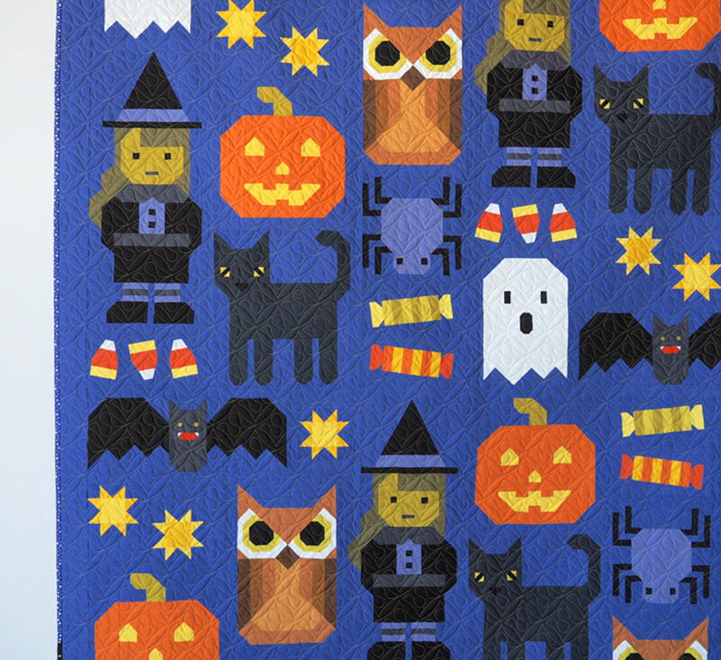 Detail of upper section of the Happy Halloween large quilt by Elizabeth Hartman showing patchwork blocks up close, including a Witch with pointed hat and striped stockings, orange Jack-o-Lantern, brown Owl with round eyes, Witch in black dress, black Cat with yellow eyes, Candy Corn, yellow Stars, and a white Ghost on cobalt blue-purple background.