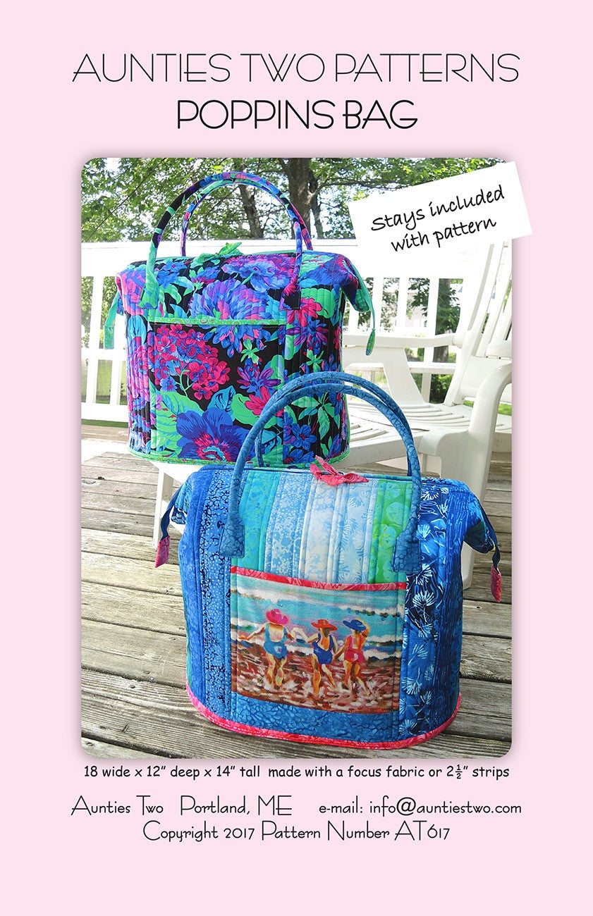 Aunties Two Patterns Poppins Bag sewing pattern (AT617) front cover: two finished Poppins Bags on a wooden deck, one in a bright pink, purple, and green floral on black, one in blue strips with a painted beach scene of three people wading on the front pocket, a tag reading Stays included with pattern, and the size line 18 inches wide by 12 inches deep by 14 inches tall, made with a focus fabric or 2 1/2 inch strips.