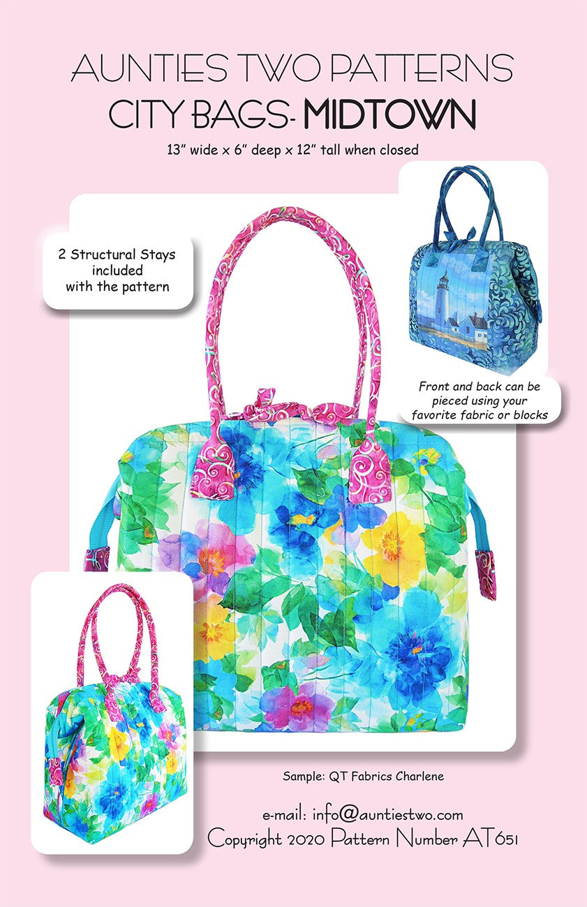 Aunties Two Patterns City Bags Midtown sewing pattern (AT651) front cover with the size 13 inches wide by 6 deep by 12 tall when closed. A finished bag in a blue, yellow, and pink watercolor floral print with pink handles, a side view of the same bag, and a smaller bag with a lighthouse scene on the front. Notes read 2 Structural Stays included with the pattern and Front and back can be pieced using your favorite fabric or blocks.