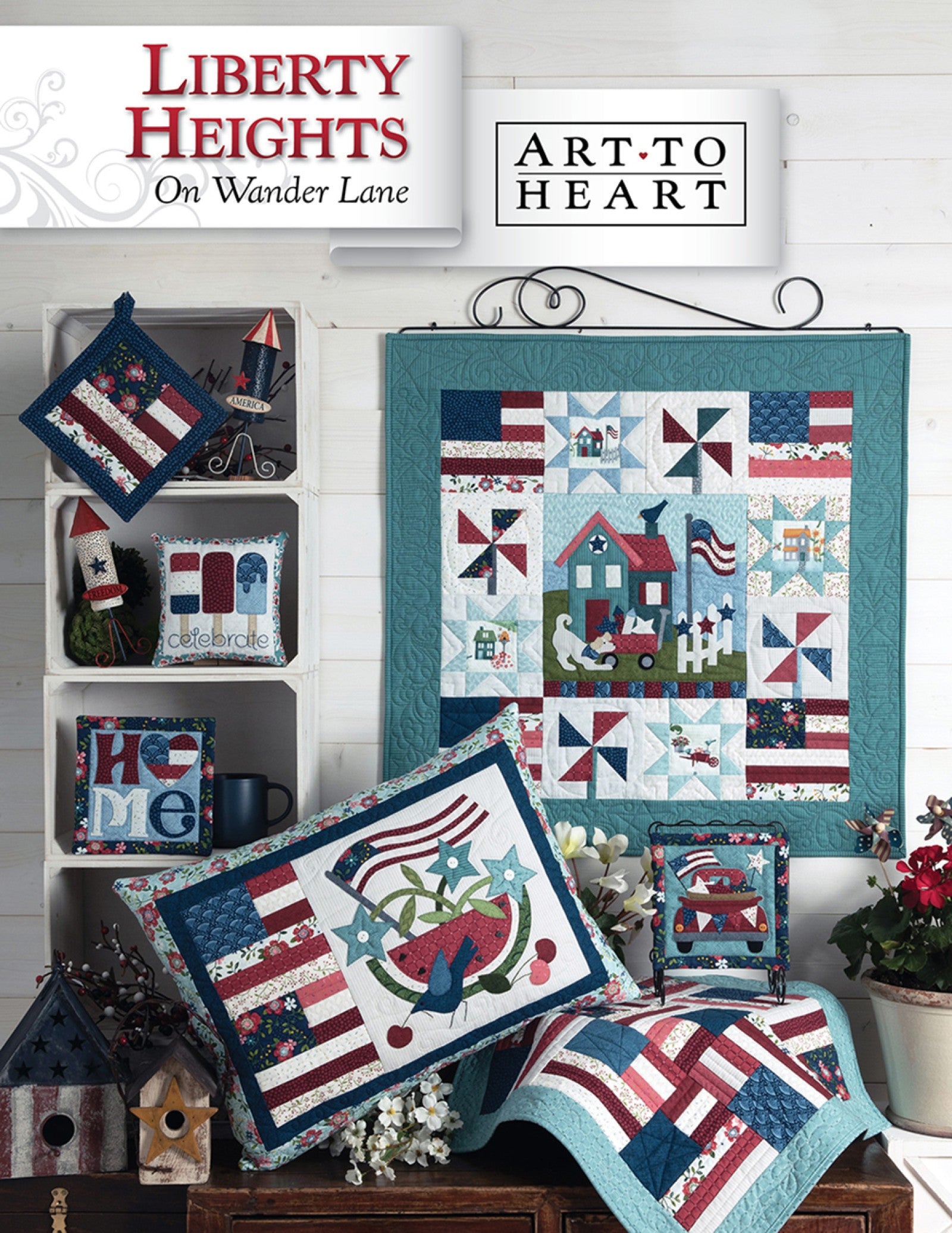 Front cover of the Liberty Heights on Wander Lane quilt pattern by Nancy Halvorsen, Art to Heart, showing the patriotic village appliqué block with flags and pinwheels framed in patchwork with red, white, and blue projects.