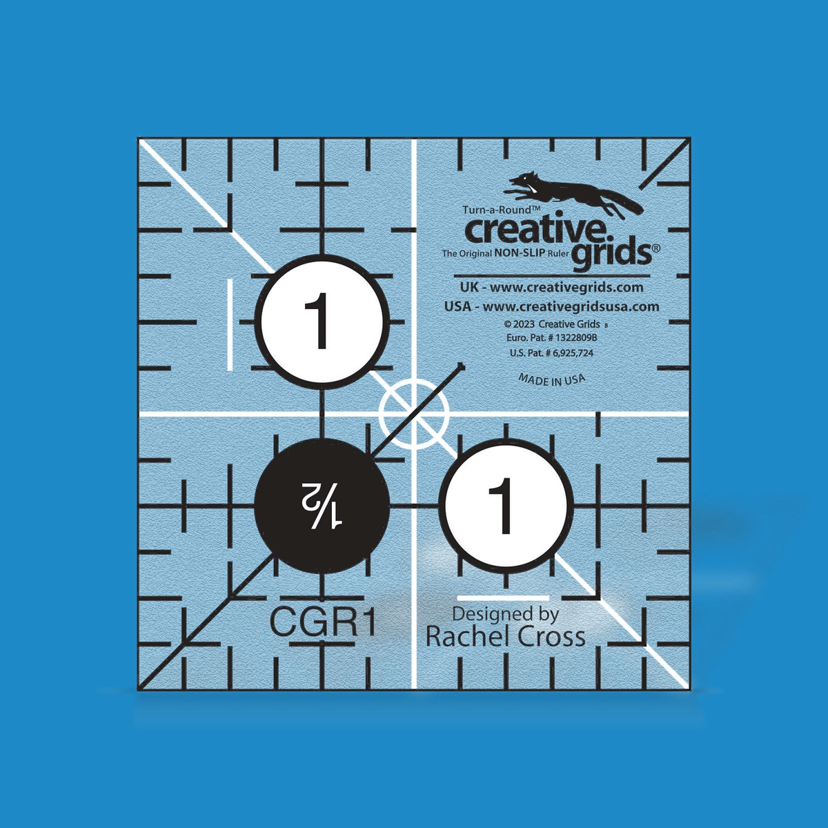 Creative Grids 1-1/2 inch square quilt ruler CGR1 by Rachel Cross rendered in translucent blue acrylic with black and white grid markings, 1 inch numbers in white dots, a 1/2 inch number in a black dot, two crossing 45 degree lines, and white centering lines.