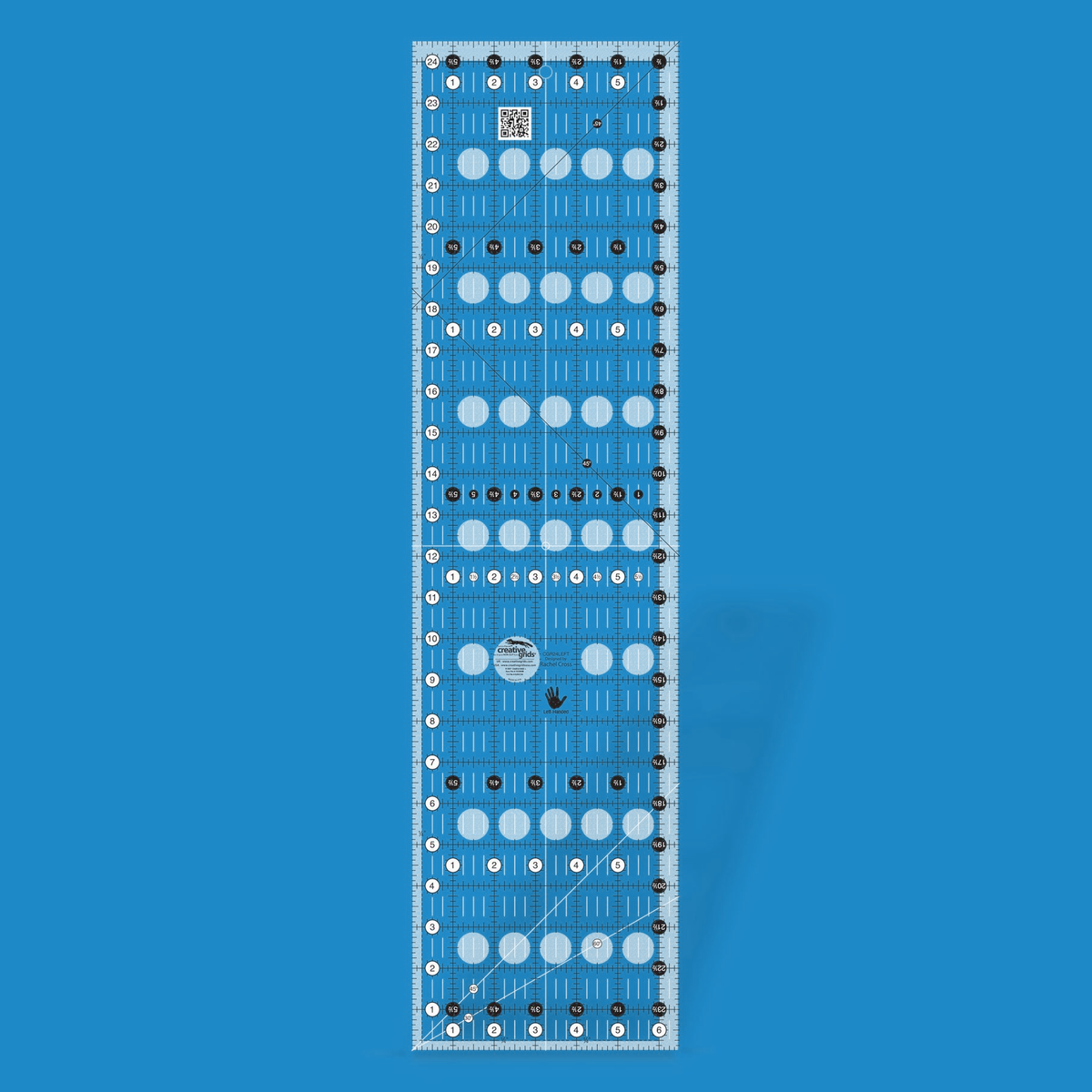 Creative Grids left handed 6-1/2 x 24-1/2 inch rectangle quilt ruler CGR24LEFT by Rachel Cross rendered in translucent blue acrylic with black and white grid markings mirrored for left-handed cutting, whole-inch numbers in white dots on the left and bottom, half-inch Turn-a-Round numbers in black dots, crossed 45 degree lines, a 30/60 degree line, a 1/4 inch dashed seam line, white centering lines, and a left-hand icon.
