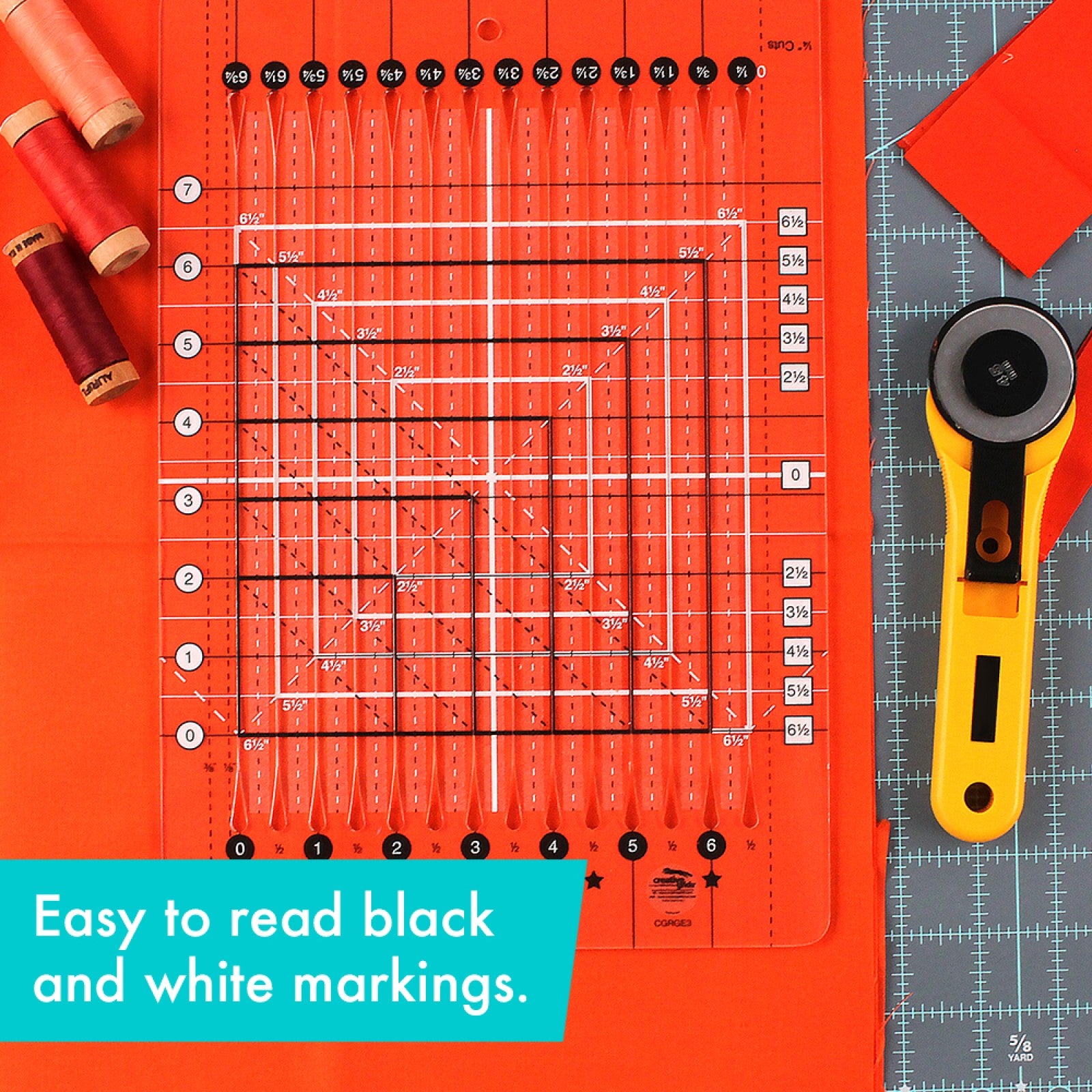 Stripology Squared Mini ruler in orange acrylic beside spools of thread and a rotary cutter, showing the easy-to-read black and white markings across the ruler.