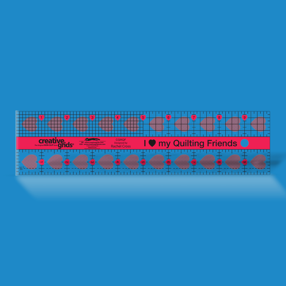 Creative Grids I Love My Quilt Friends ruler CGRQF by Rachel Cross on a blue background: pink center band printed I heart my Quilting Friends, 1/8 inch and 1/4 inch grids on the top row, a 1 inch grid with a dashed 1/4 inch line on the bottom row, and inch numbers 1 to 9 in pink hearts.