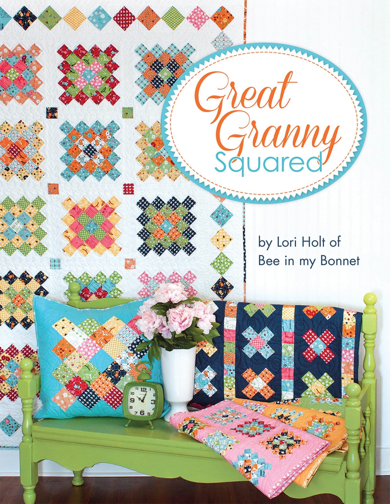 Front cover of the Great Granny Squared quilt pattern book by Lori Holt for It's Sew Emma, showing a scrappy granny-square sampler quilt on a white wall above a green bench with a turquoise granny-block pillow, a navy-bordered quilt draped behind, a folded pink quilt, a vintage green clock, and pink peonies in a white vase.
