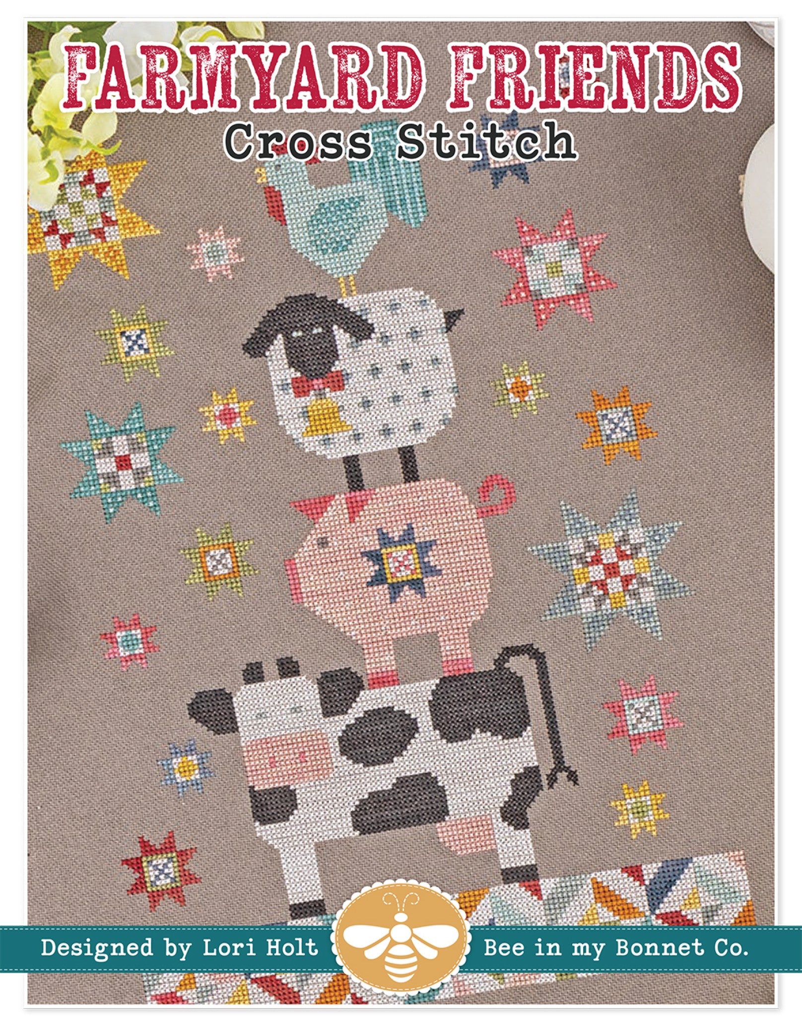 Front cover of Farmyard Friends cross stitch pattern by Lori Holt for It's Sew Emma. Four cross stitch farm animals balance in a tower, a black-and-white cow at the bottom, a pink pig with a star block, a sheep with a bell, and a teal rooster on top, surrounded by scrappy quilt-block stars on a taupe background.