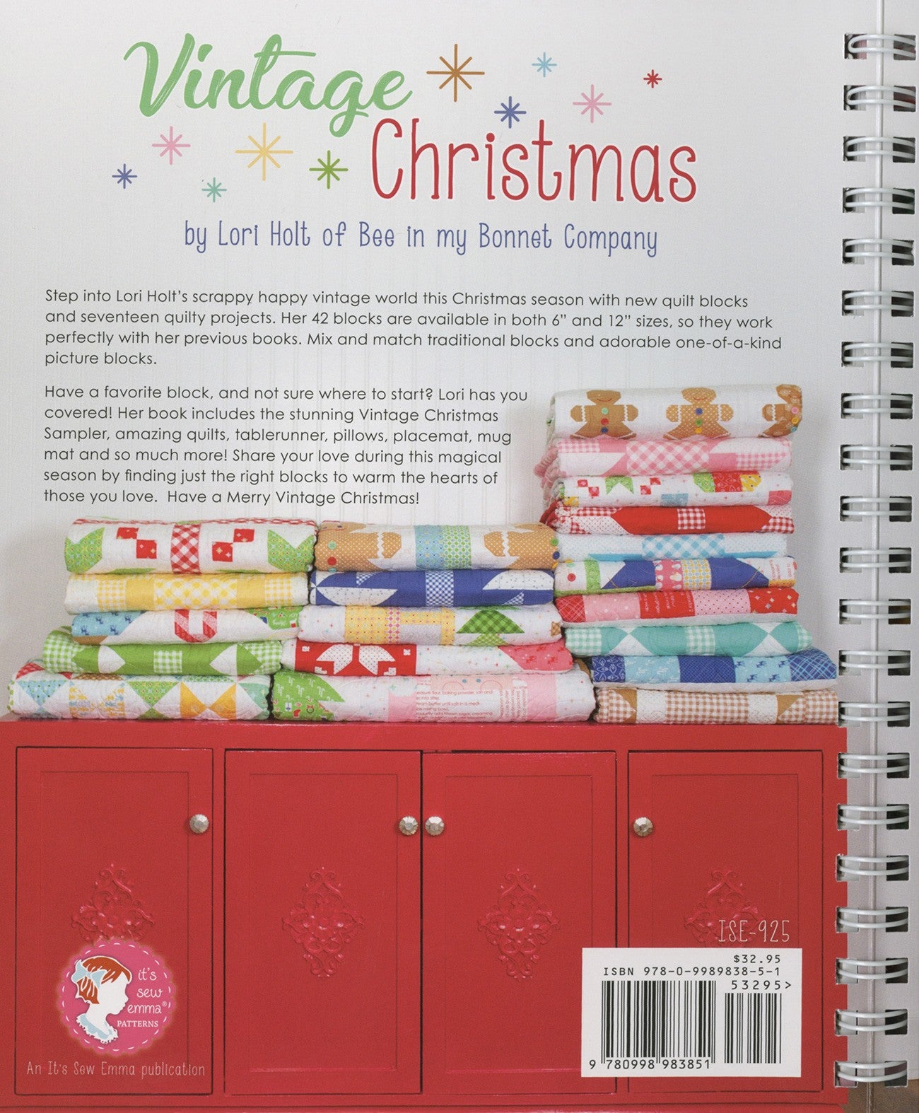 Back cover of Vintage Christmas by Lori Holt for It's Sew Emma. Stacks of folded scrappy Christmas quilts sit on a red cabinet, with the It's Sew Emma logo and item number ISE-925.