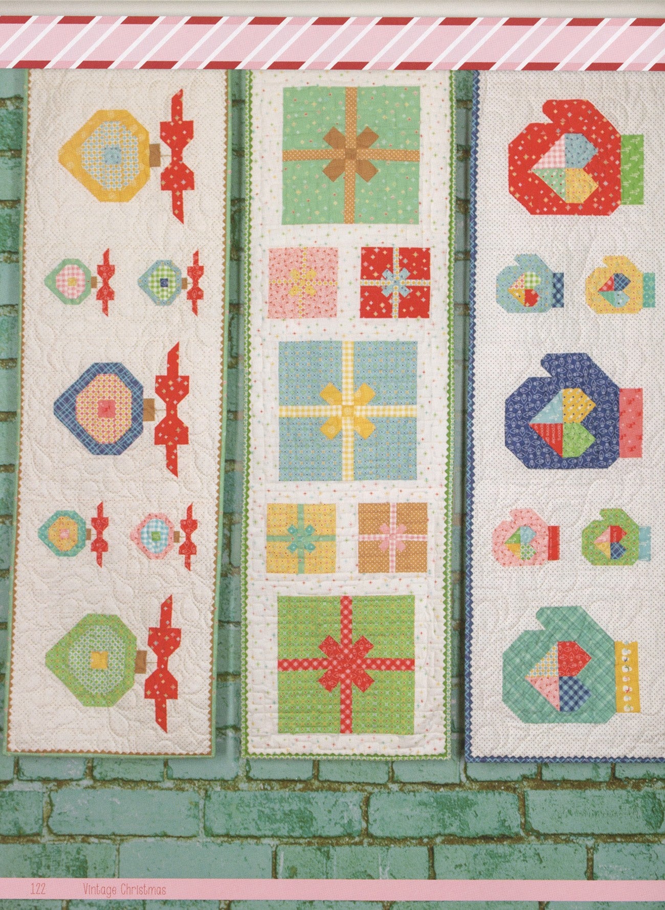 Three Christmas table runners from Vintage Christmas by Lori Holt for It's Sew Emma hanging on a green brick wall: an ornaments runner, a wrapped-presents runner, and a mittens runner.