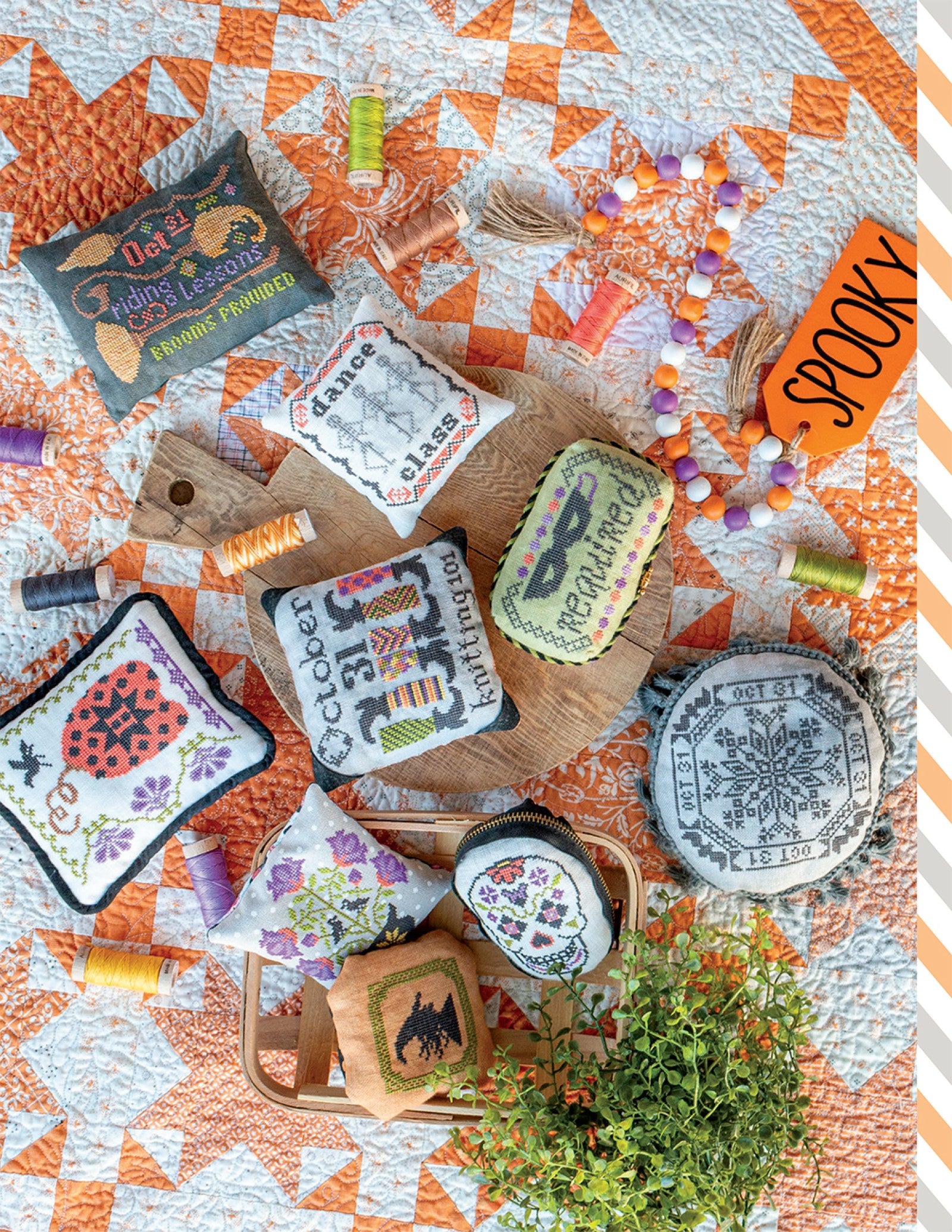 Finished Halloween cross stitch pieces from Halloween Memories, including samplers and small pin keeps in orange, black, and purple.