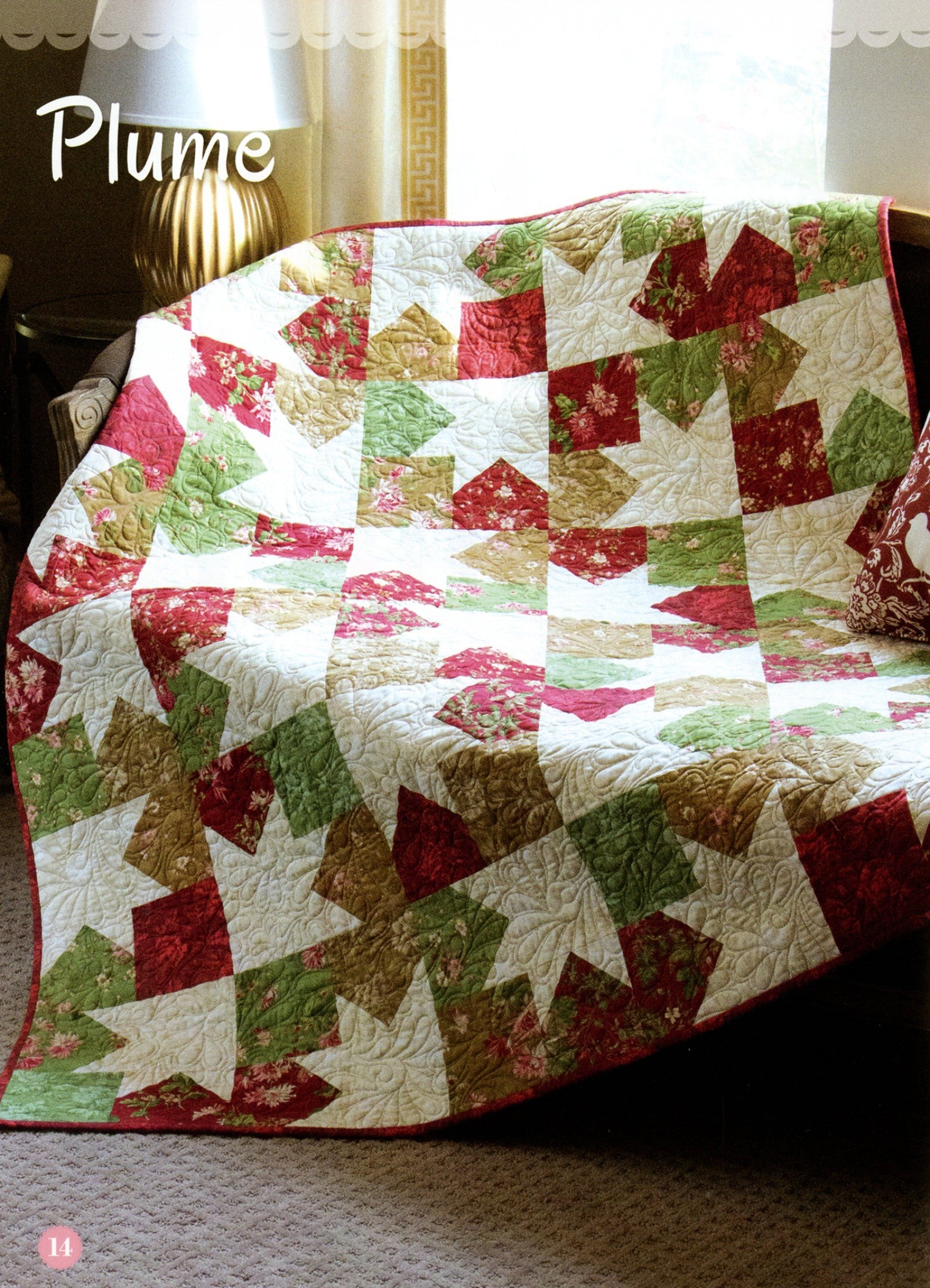 Plume quilt from the Fat Quarter Style pattern book, a pieced star design in red, green, and cream fat quarter prints draped on a bench.