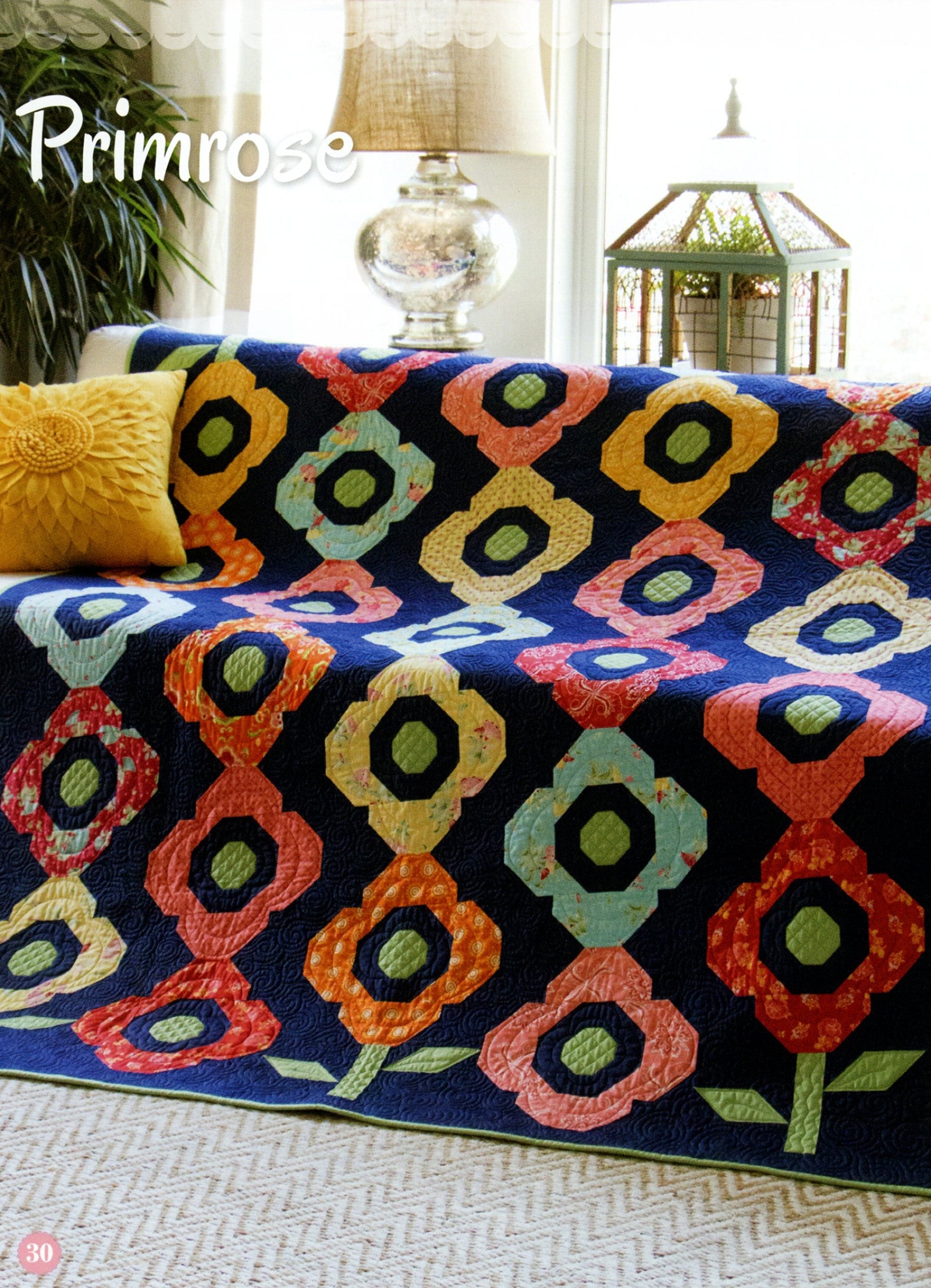 Primrose quilt from the Fat Quarter Style pattern book, snowball flower blocks in orange, coral, gold, and aqua on a navy background.