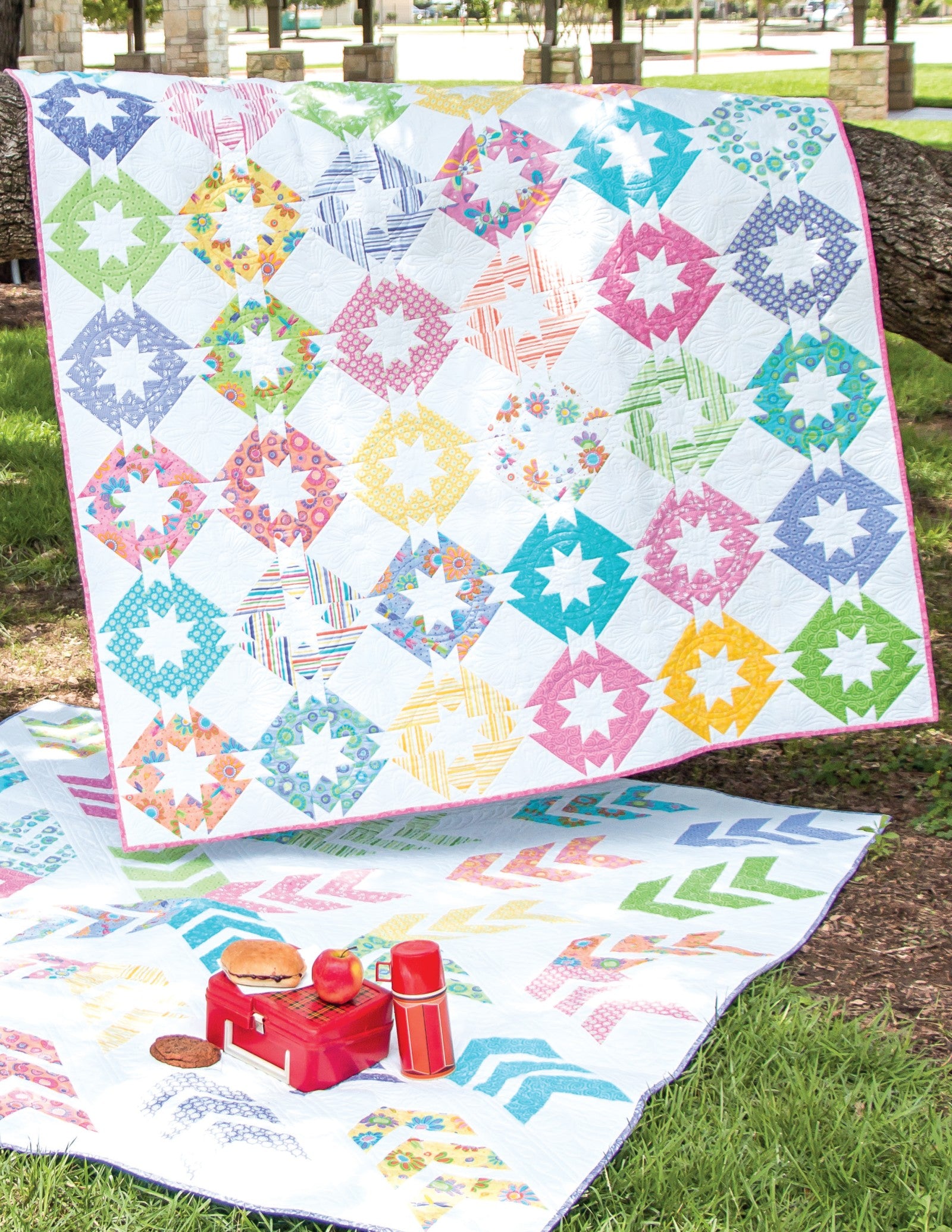 Interior quilt from Precut Primer, white background with scrappy star and wreath blocks in bright precut prints, shown outdoors.