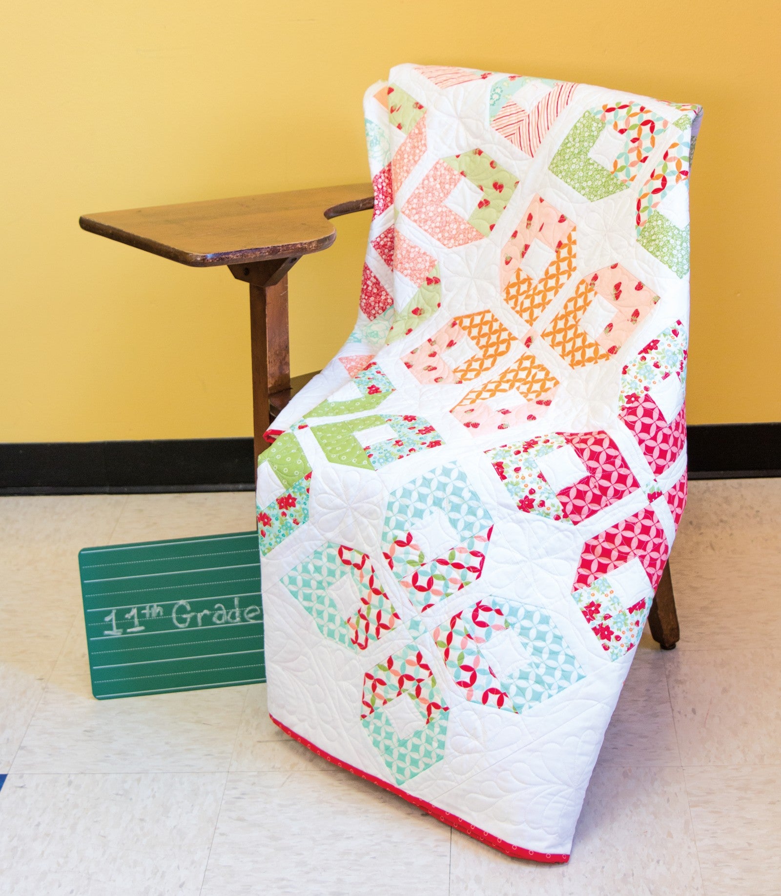 Interior quilt from Precut Primer, spool and bowtie blocks in bright prints draped on a chair.