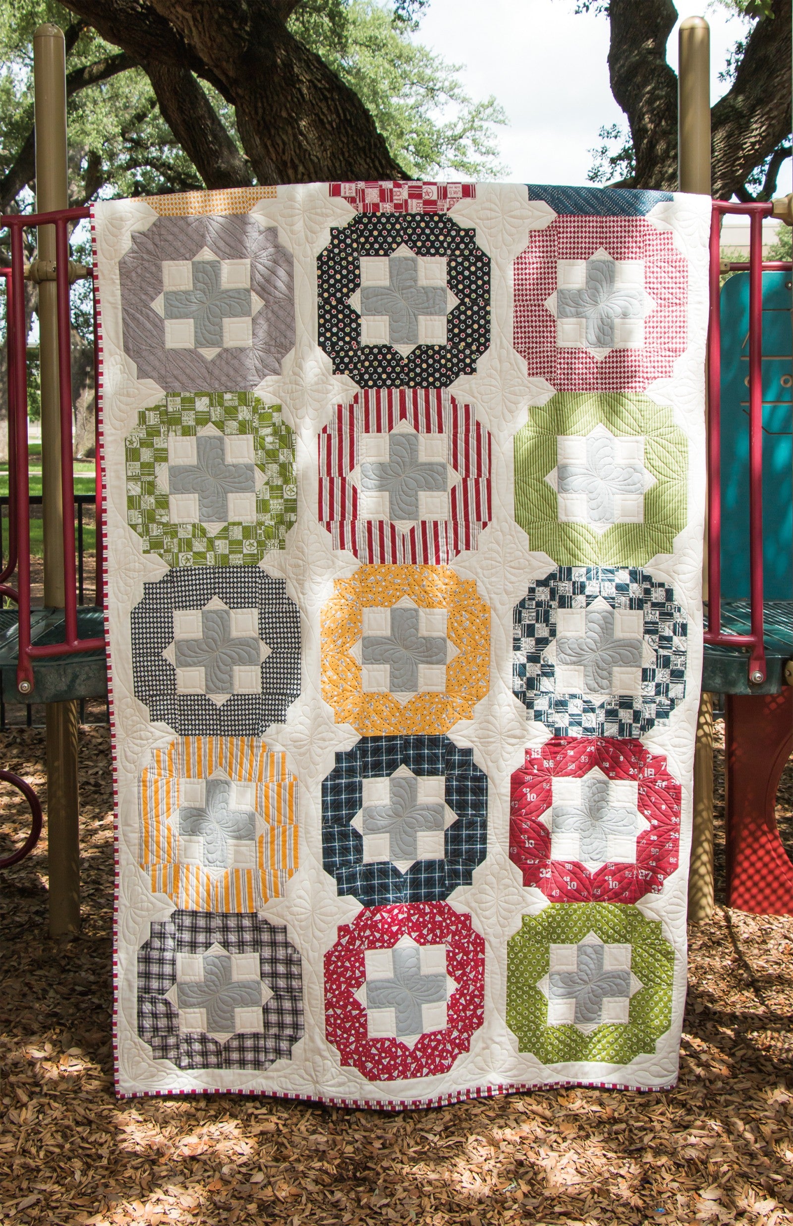 Interior quilt from Precut Primer, plus and cross blocks in gray, gold, pink, and green prints.