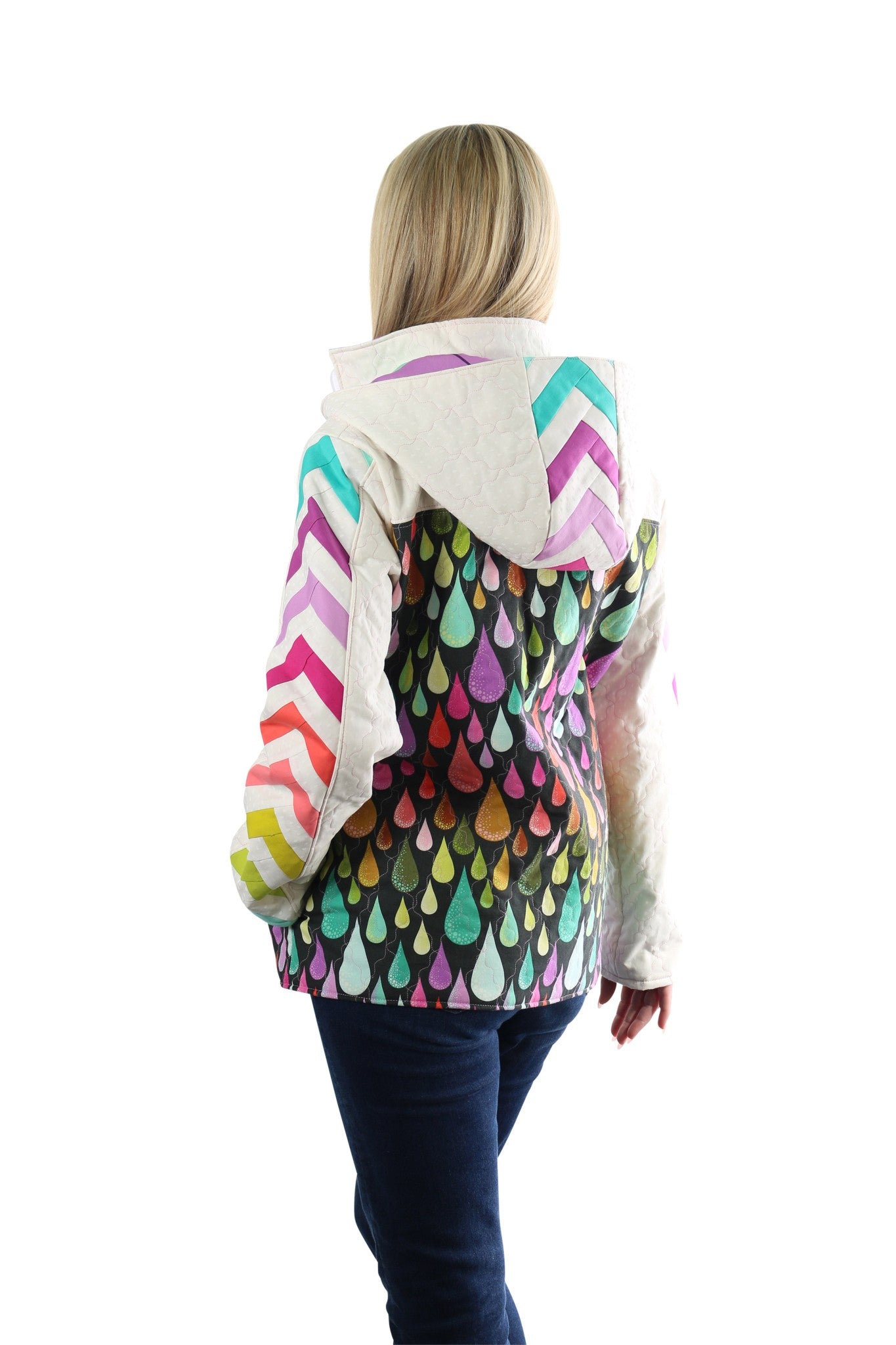 Back view of a person wearing a Bella Quilt Coat with the hood down, the rainbow chevron hood resting against a raindrop-print quilted back.