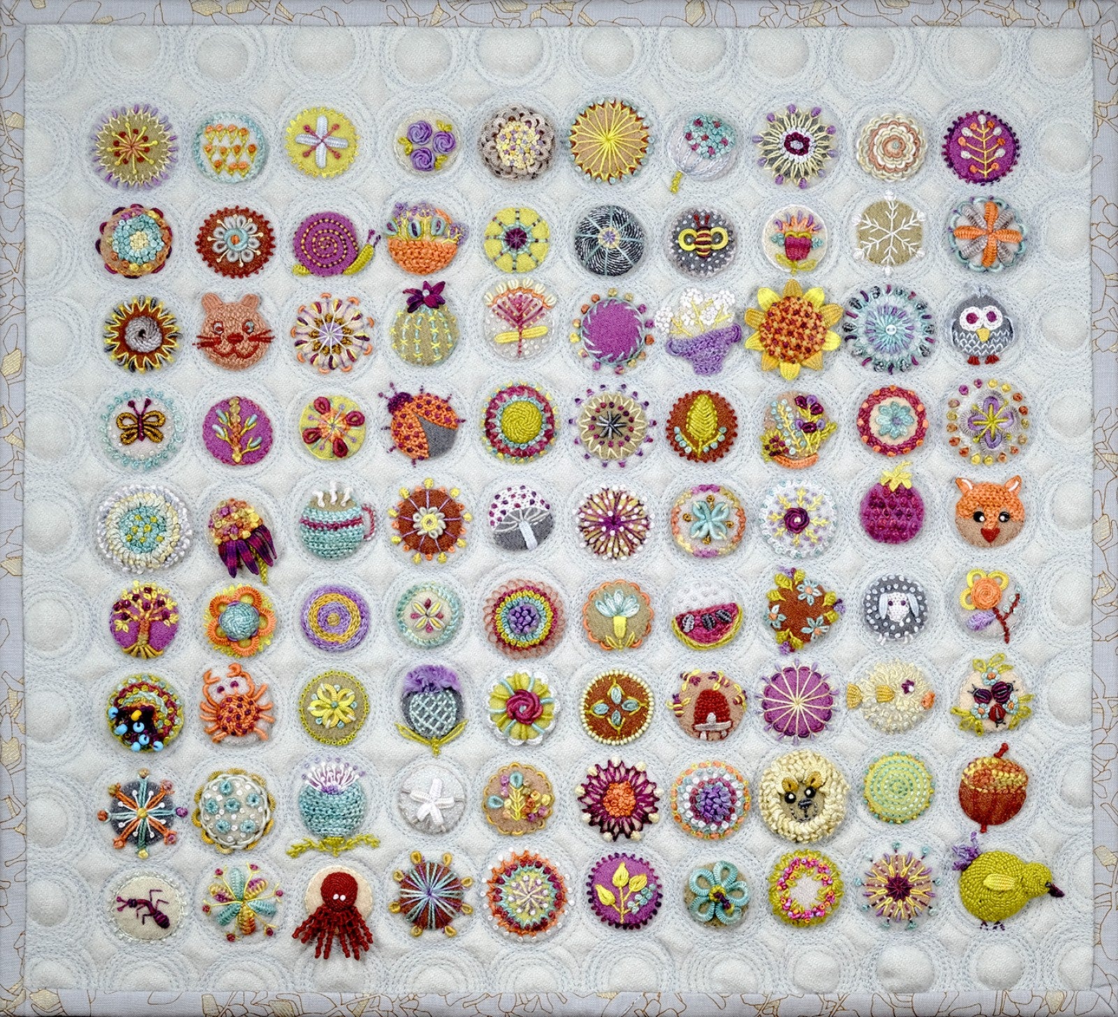 Close detail of the finished Toned Down Circle Sampler by Sue Spargo of Folk Art Quilts, showing rows of individually embroidered wool circles, each a different design worked in perle cotton with beads and dimensional stitches, on a circle-quilted neutral background.
