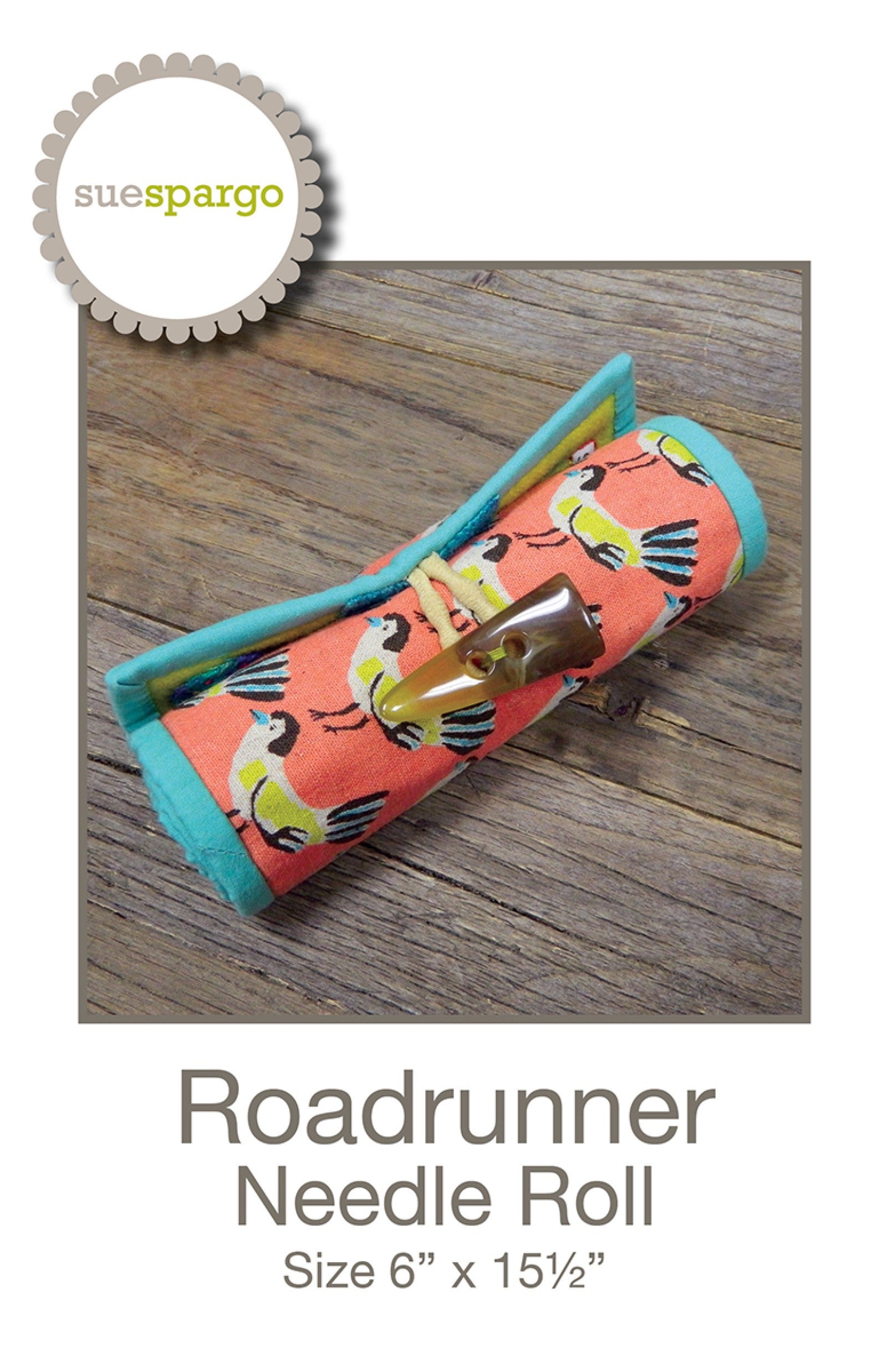 Roadrunner Needle Roll sewing pattern by Sue Spargo of Folk Art Quilts. Front cover shows the finished needle roll in coral bird-print canvas with turquoise binding, rolled and closed with a corded loop over a horn button, resting on weathered wood. Title and size 6 by 15-1/2 inches shown.