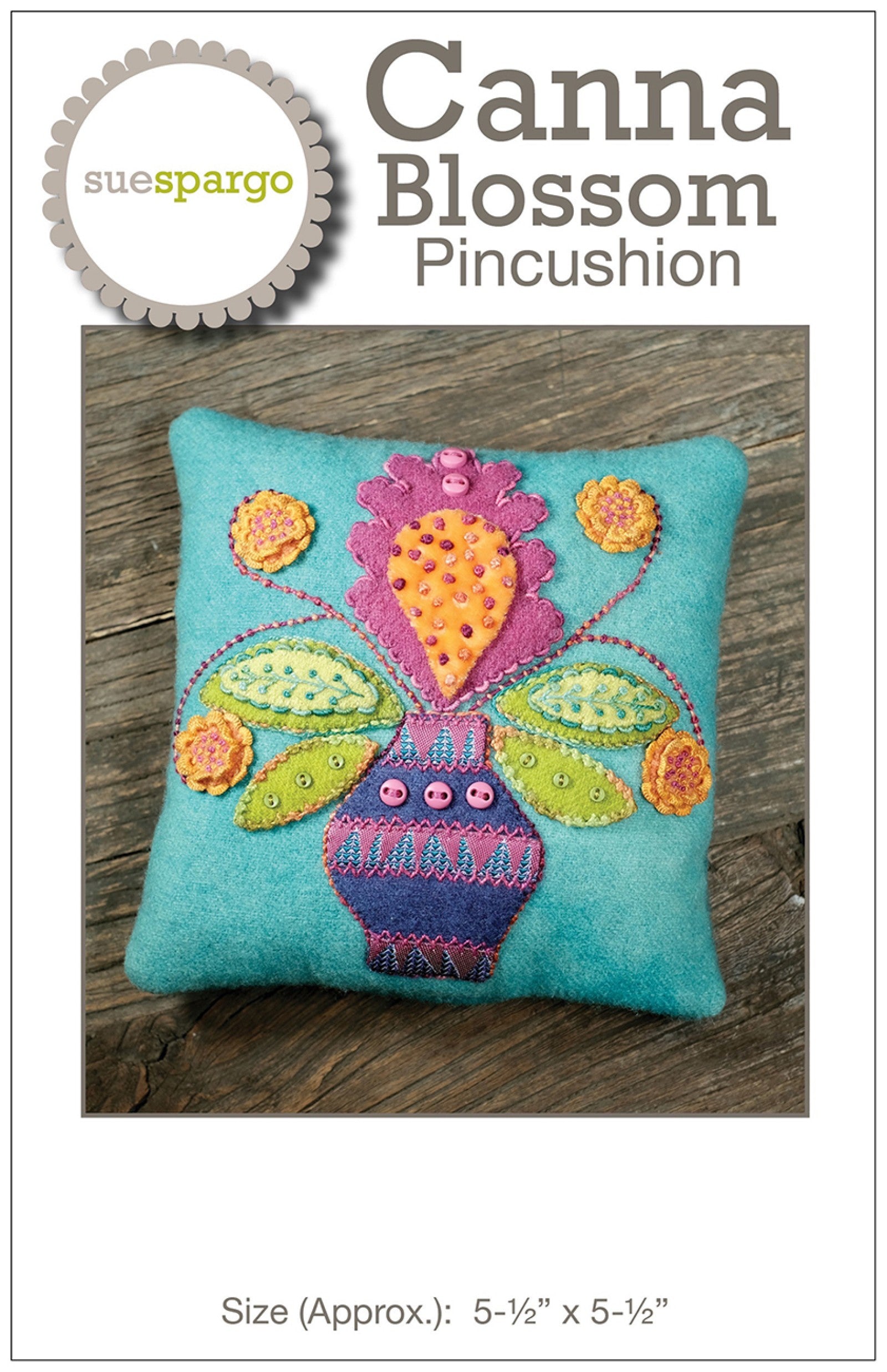 Canna Blossom Pincushion sewing pattern by Sue Spargo of Folk Art Quilts. Cover shows the finished square pincushion in turquoise wool with a folk-art canna flower in magenta and orange rising from a patterned vase, flanked by layered green leaves and small accent flowers, worked in wool and velvet appliqué with dimensional embroidery and buttons. Size about 5-1/2 inches square shown.