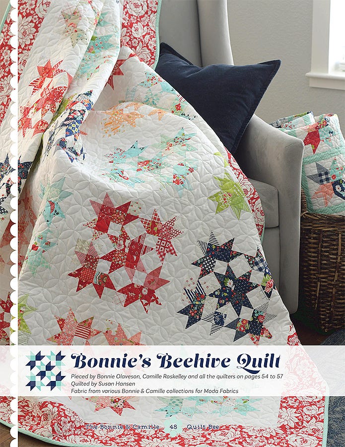 Bonnie's Beehive Quilt from The Bonnie & Camille Quilt Bee, red and navy star blocks draped on a sofa.