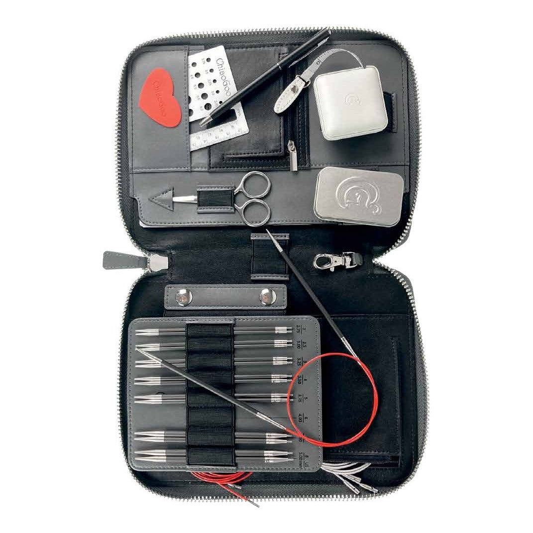 ChiaoGoo FORTÉ 2.0 set case open from above: needle board with the carbon fiber and Blackwood tips in elastic loops, a red TWIST cable and silver SWIV360 cables, scissors, tape measure, swatch gauge, gripper, and the metal accessory tin in the pockets