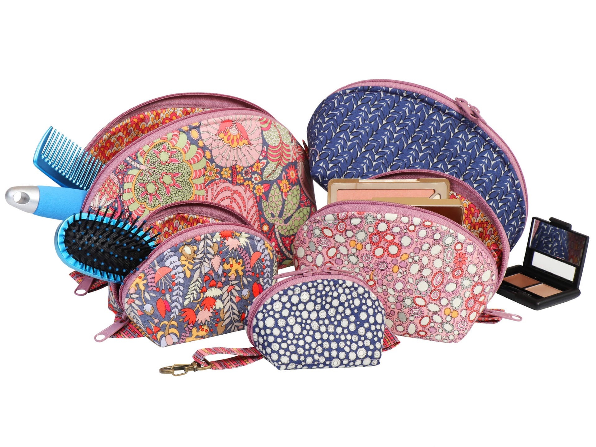 Clam Up pouches shown with makeup, brushes, and a comb to show their use as cosmetic bags.