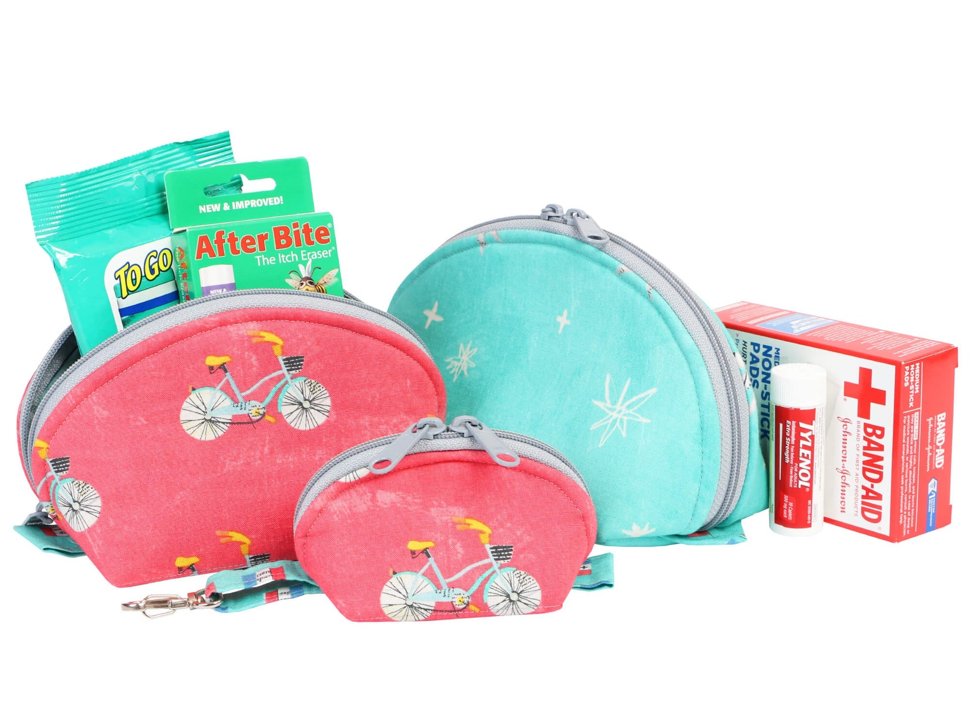 Clam Up pouches in a bicycle print shown with travel and first-aid items beside them.