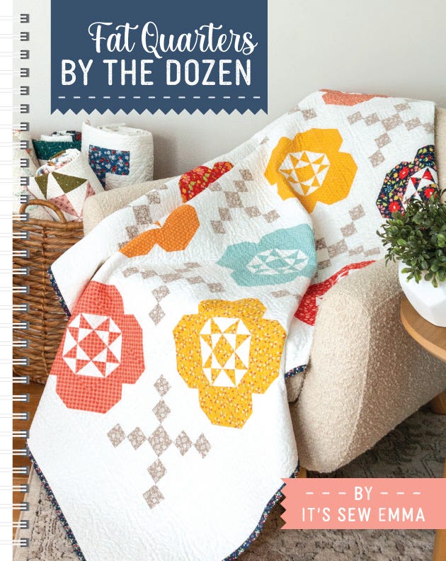 Front cover of Fat Quarters by the Dozen Quilt Pattern Book from It's Sew Emma, a spiral-bound book showing a quilt with pieced orange and gold blooms draped over an armchair.