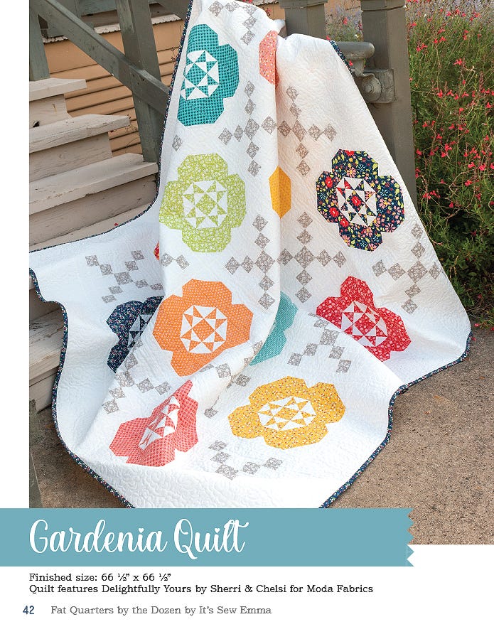 The Gardenia quilt, 66.5 x 66.5 inches square, large pieced blooms in orange, teal, and gold linked by a cream chain.