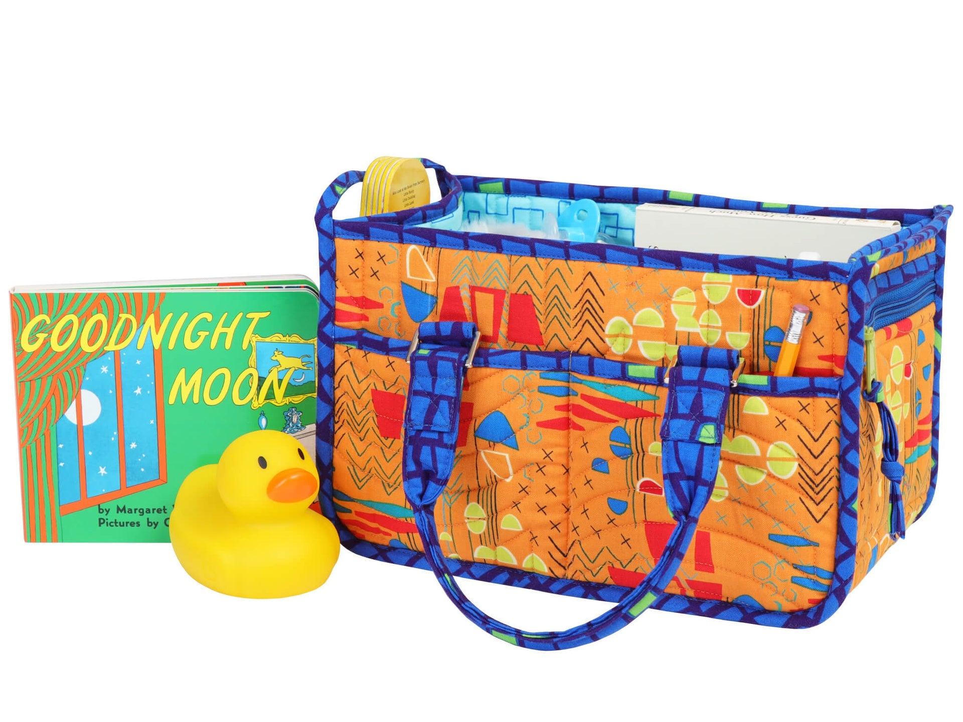 In Control Caddy sewn in a bright orange print, holding a Goodnight Moon book and a rubber duck, used as a small nursery and diaper caddy.