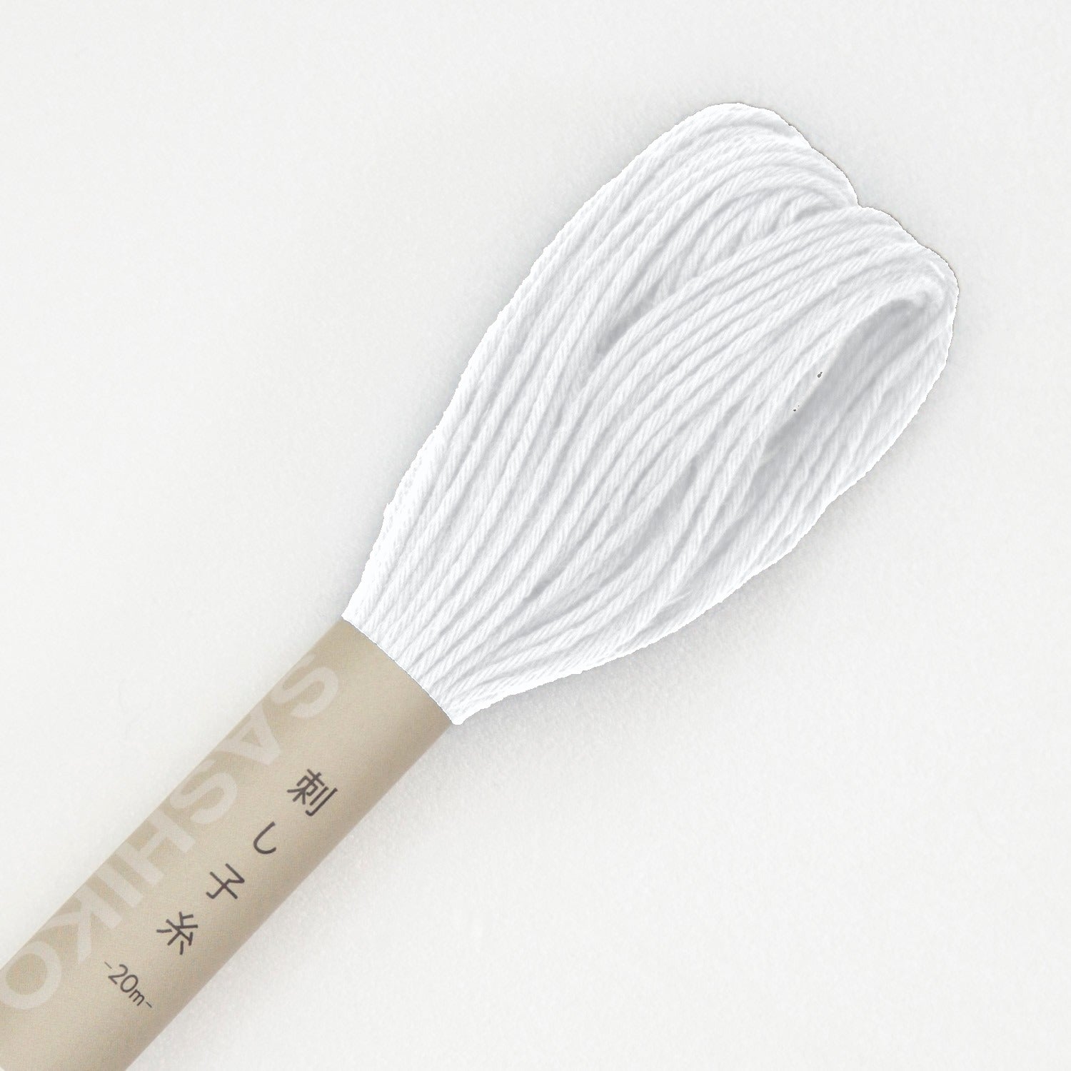 Olympus sashiko thread in white, a close view of the looped end of a white cotton skein above its kraft SASHIKO paper band, on a white background.