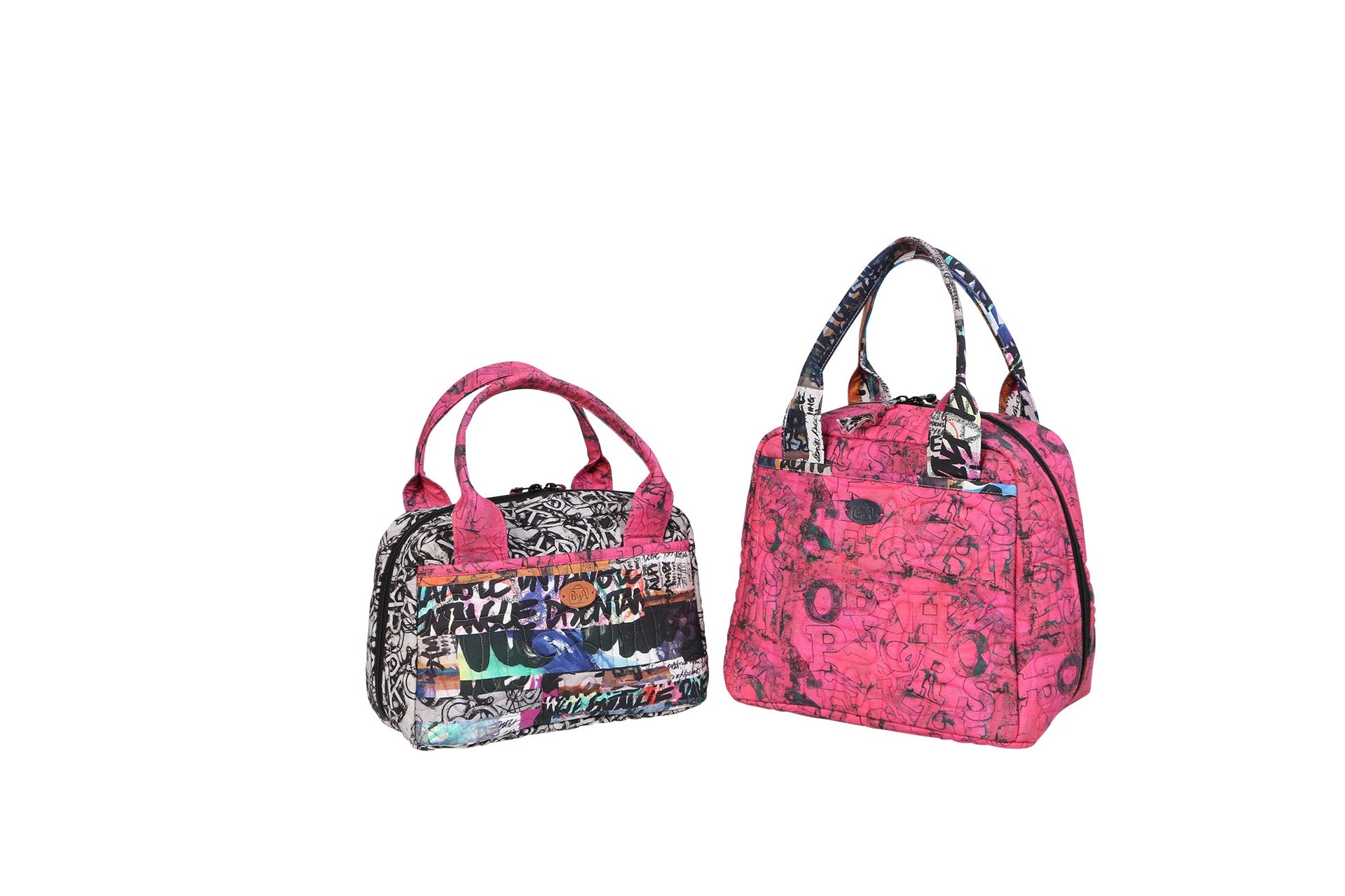 Two finished Out to Lunch bags side by side, a small graffiti-print bag and a larger pink bag, each with rolled handles and a wraparound zipper.