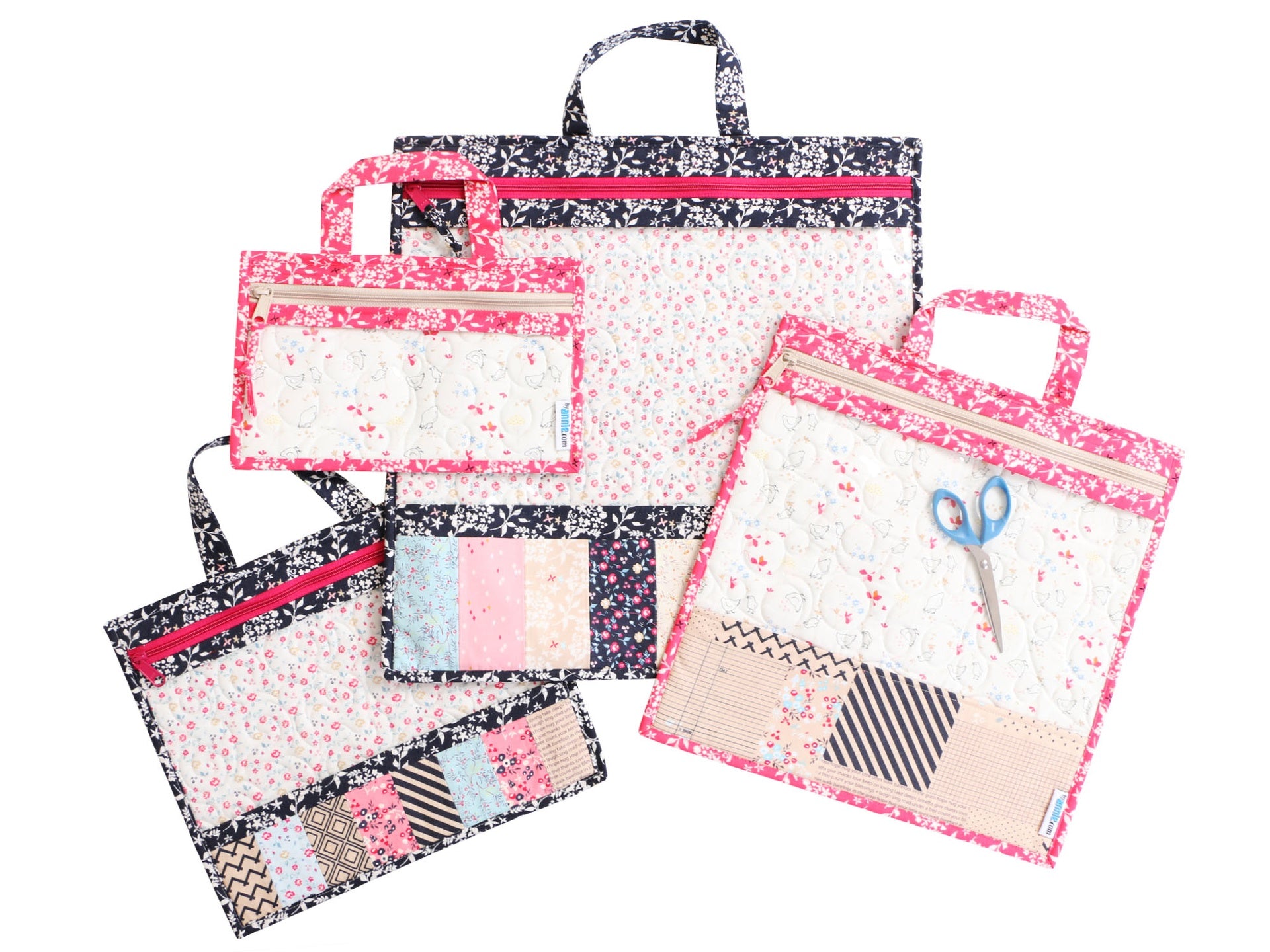 Four Project Bags in black and pink prints in graduated sizes, with scissors, fabric, and notions visible through the vinyl fronts.
