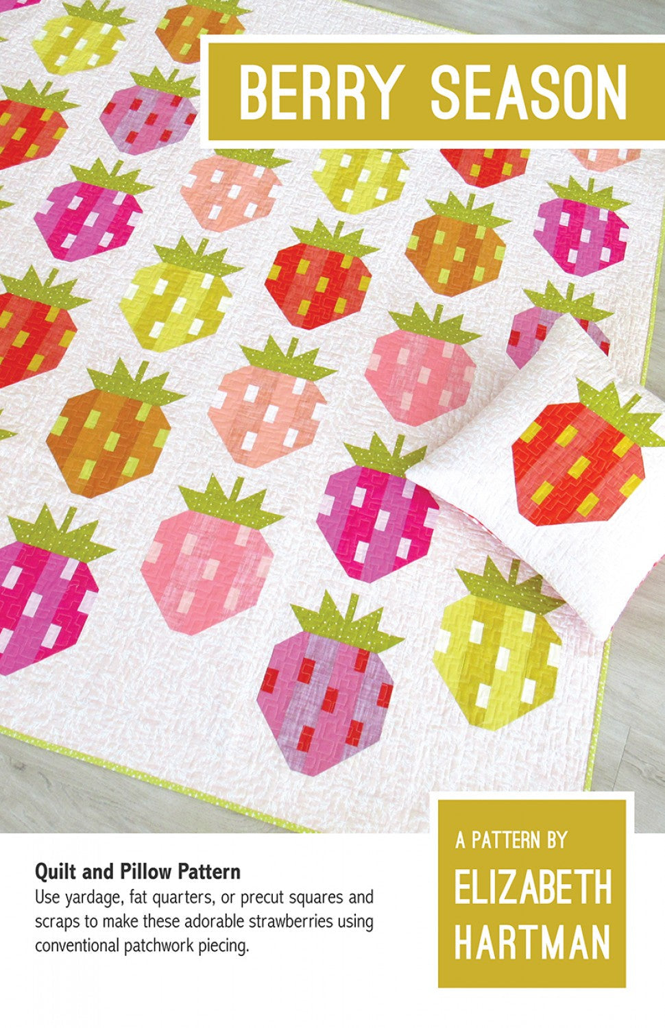 Berry Season quilt pattern cover by Elizabeth Hartman. The quilt is displayed draped on a surface showing patchwork strawberries in a full rainbow of colors including red, hot pink, coral, peach, orange, yellow, chartreuse, and violet on a white background. Each berry has two coordinating body fabrics, cream seed details, and green stems.