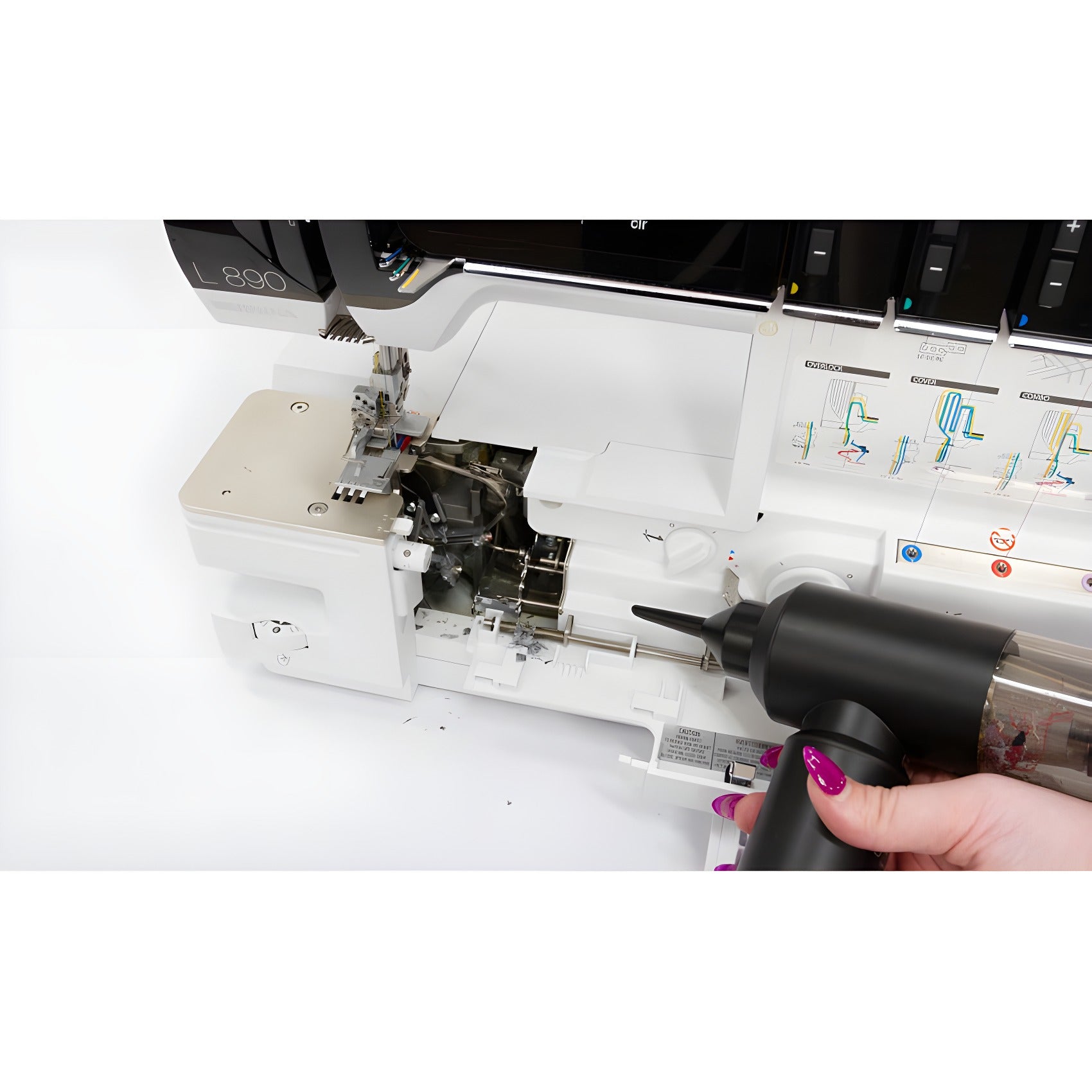 A person holding the SewClean vacuum with a narrow nozzle at the open looper area of a serger, clearing lint from around the loopers and needle plate.