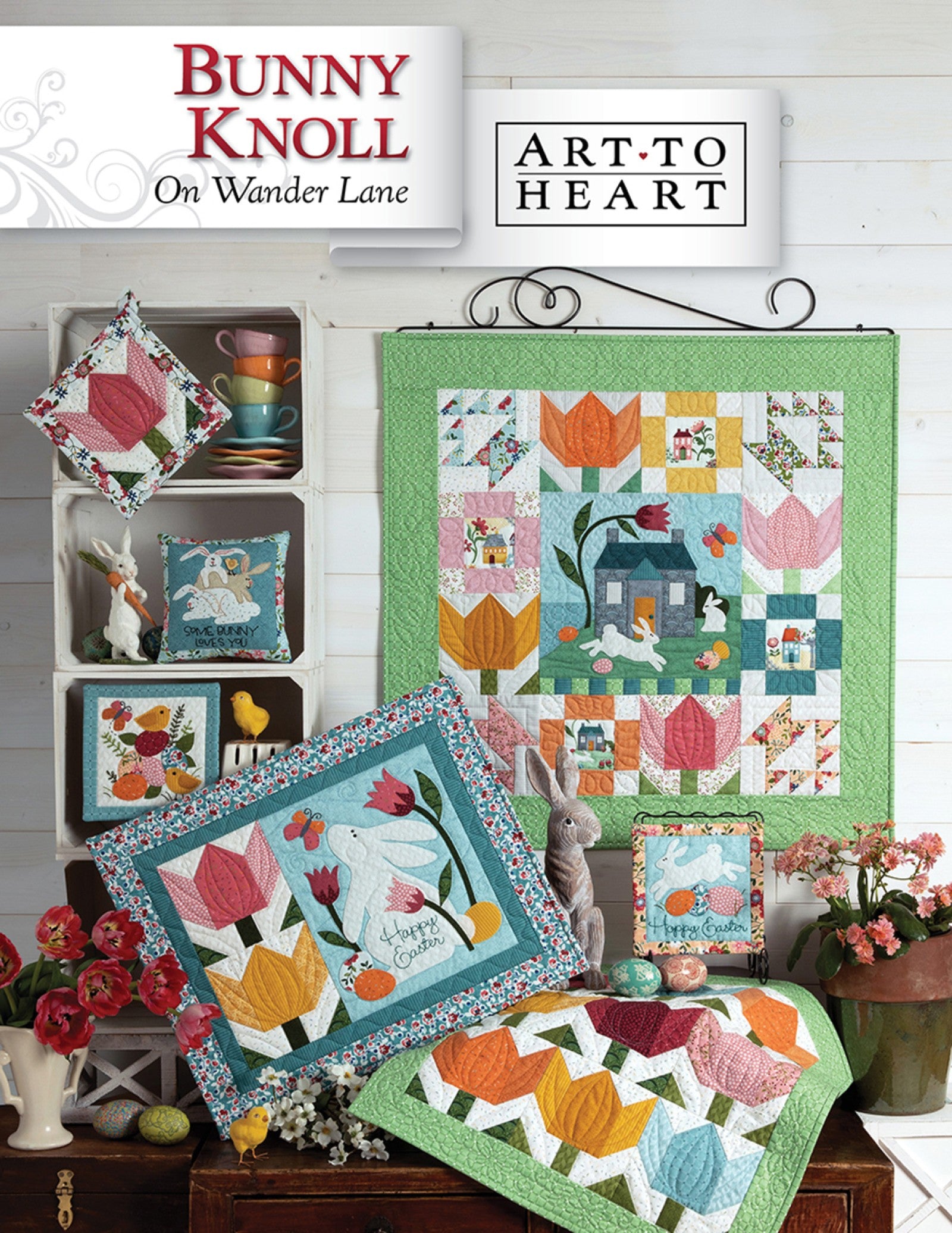 Front cover of the Bunny Knoll on Wander Lane quilt pattern by Nancy Halvorsen, Art to Heart, showing the tulip and bunny appliqué block framed in patchwork with a tulip table runner and pastel spring projects.