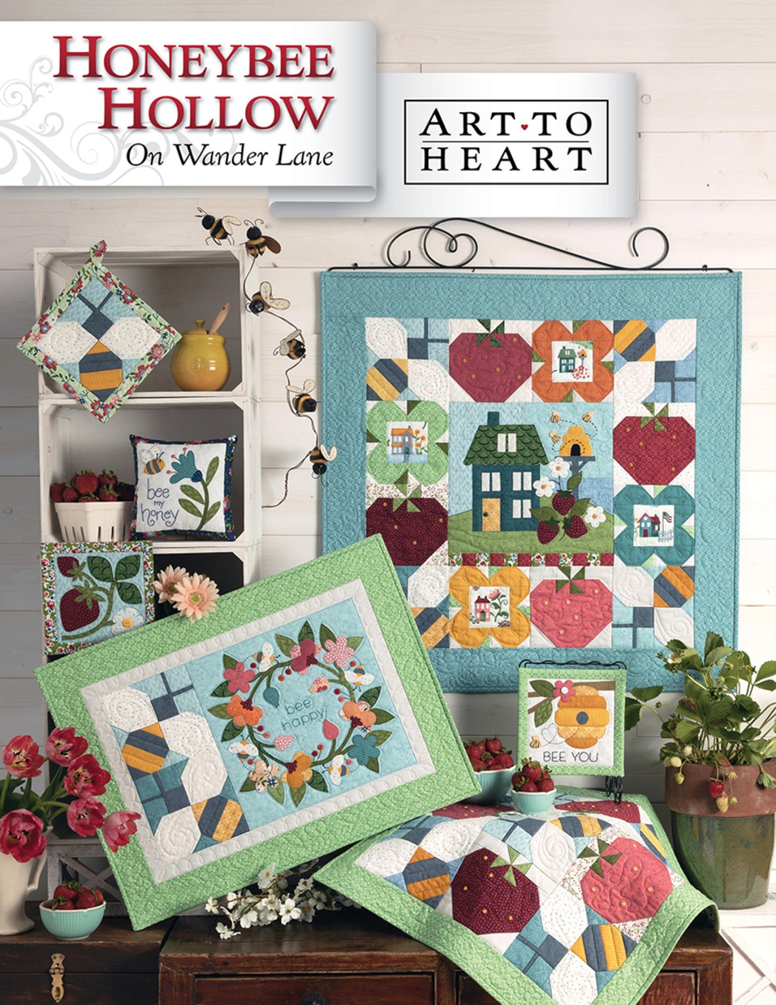 Front cover of the Honeybee Hollow on Wander Lane quilt pattern by Nancy Halvorsen, Art to Heart, showing the bee, apple, and strawberry appliqué block framed in patchwork with Bee You projects in bright summer colors.