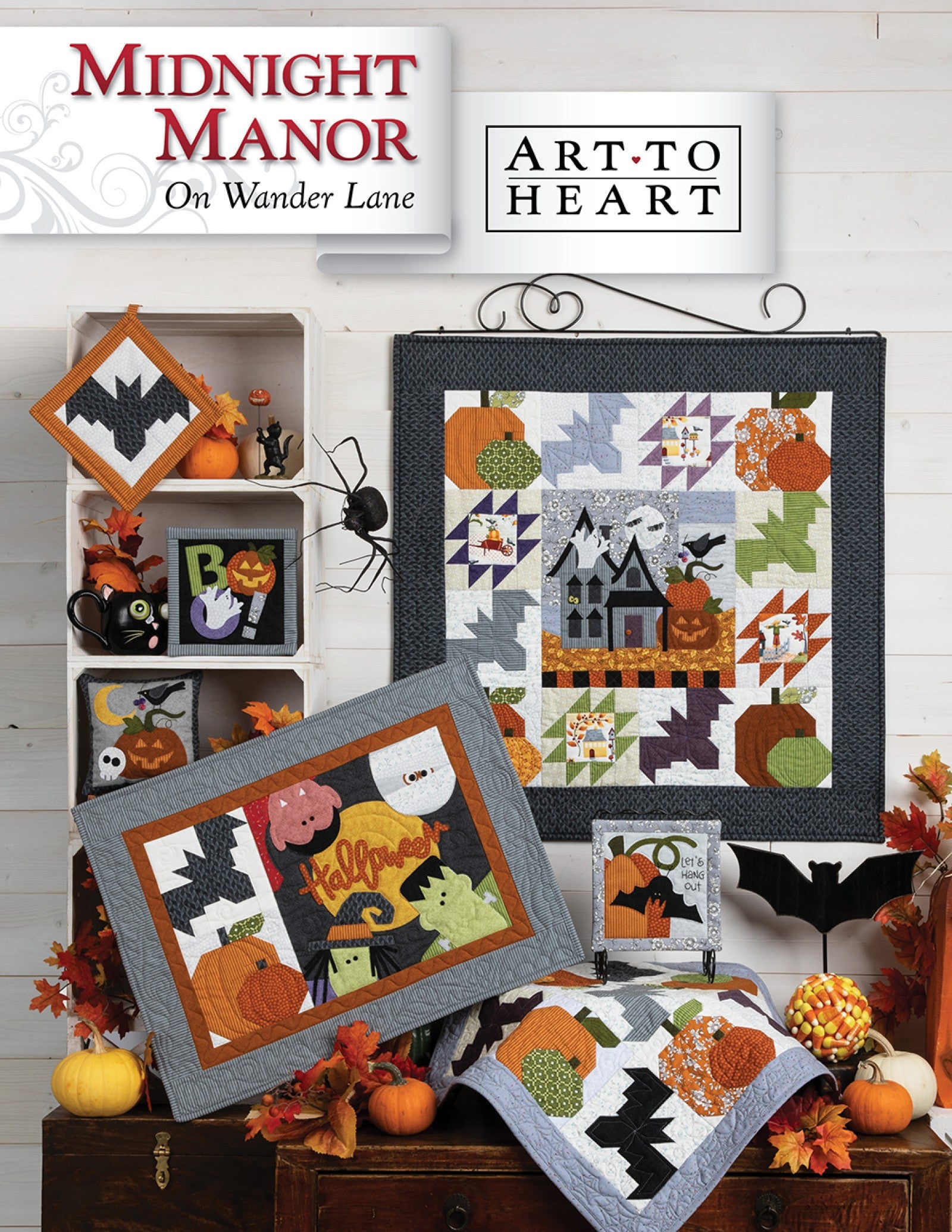 Front cover of the Midnight Manor on Wander Lane quilt pattern by Nancy Halvorsen, Art to Heart, showing the haunted house Halloween appliqué block framed in patchwork with jack-o-lantern and bat projects in dark autumn tones.