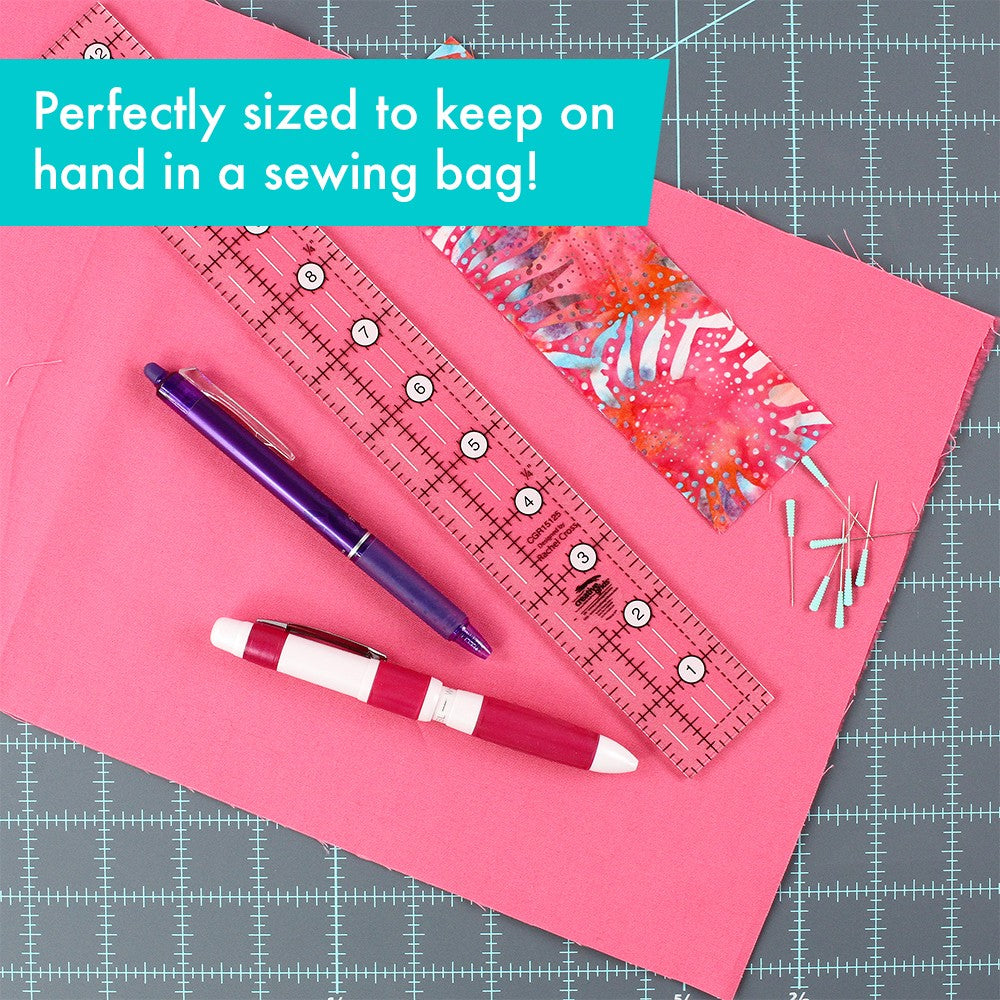 Creative Grids 1-1/2 x 12-1/2 inch ruler CGR15125 on pink fabric on a cutting mat beside pens, pins, and a fabric strip, with a brand caption about keeping it in a sewing bag.