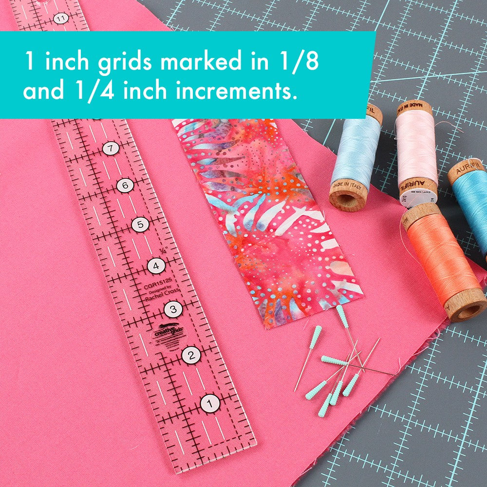 Creative Grids 1-1/2 x 12-1/2 inch ruler CGR15125 on pink fabric beside spools of thread, with a brand caption about the 1 inch grid marked in 1/8 and 1/4 inch increments.