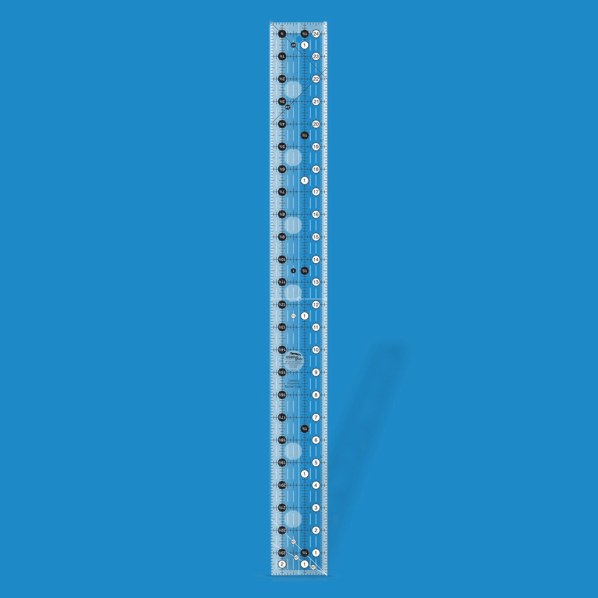Creative Grids 2-1/2 x 24-1/2 inch rectangle quilt ruler CGR224 by Rachel Cross rendered in translucent blue acrylic with black and white grid markings, whole-inch numbers in white dots, half-inch Turn-a-Round numbers in black dots, crossed 45 degree lines, a 30/60 degree line, a 1/4 inch dashed seam line, and white centering lines.