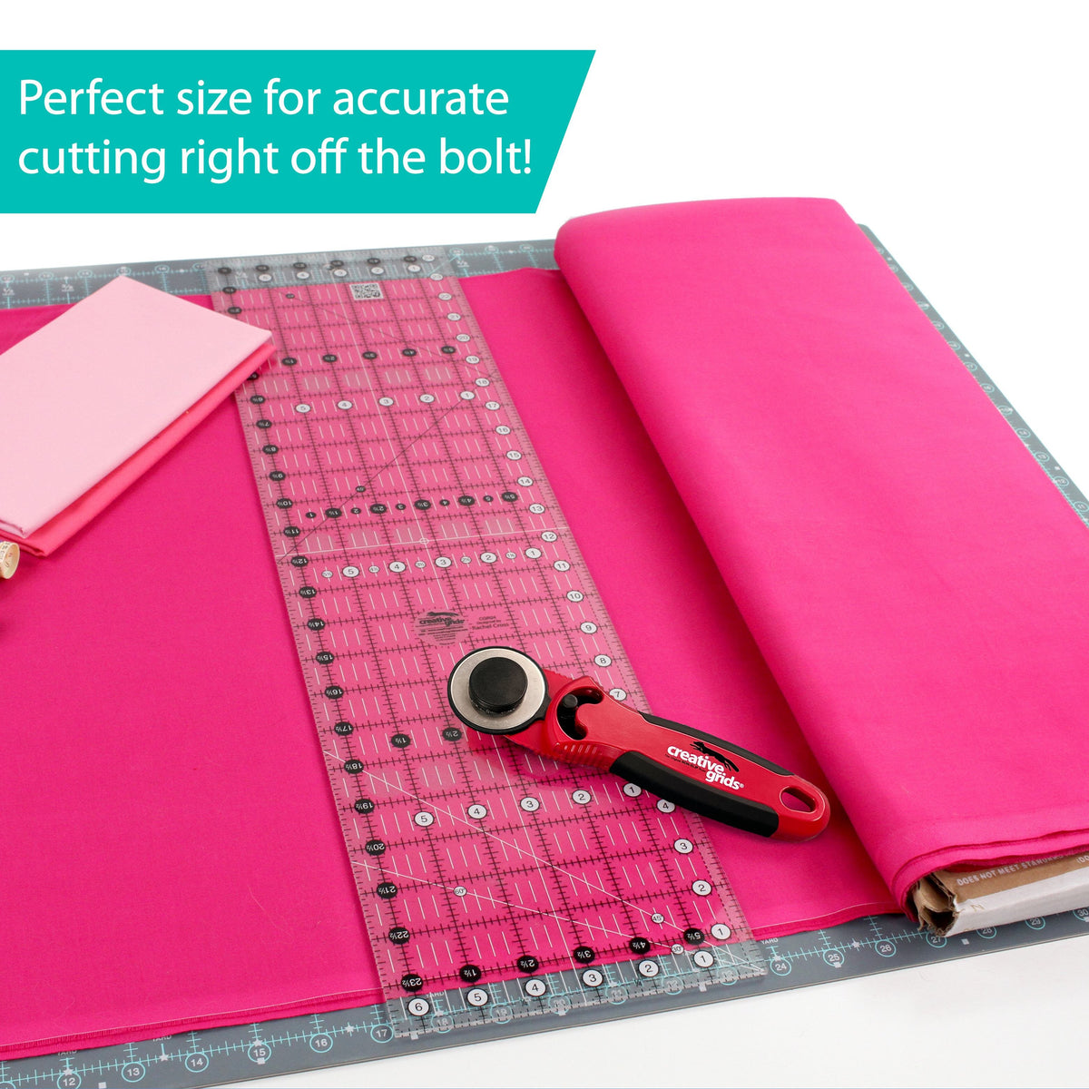 Creative Grids 6-1/2 x 24-1/2 inch ruler CGR24 laid on hot pink fabric unrolled from the bolt on a cutting mat with a rotary cutter, captioned Perfect size for accurate cutting right off the bolt.