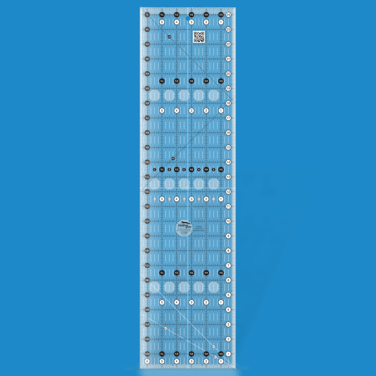 Creative Grids 6-1/2 x 24-1/2 inch rectangle quilt ruler CGR24 by Rachel Cross rendered in translucent blue acrylic with black and white grid markings, whole-inch numbers in white dots, half-inch Turn-a-Round numbers in black dots, crossed 45 degree lines, a 30/60 degree line, a 1/4 inch dashed seam line, and white centering lines.