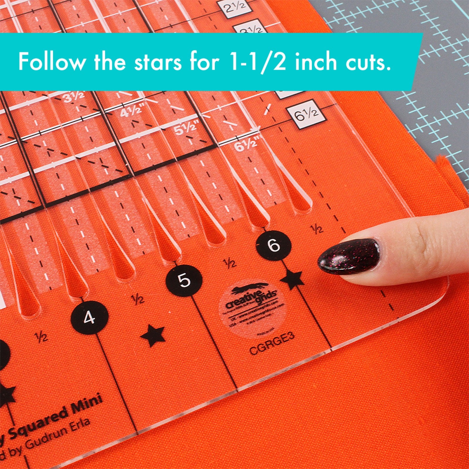 Close-up of the Stripology Squared Mini ruler's star markings used for 1 1/2 inch cuts, with a finger pointing to the star at the 6 inch line over orange fabric.