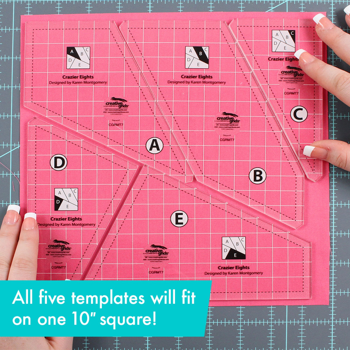 All five Creative Grids Crazier Eights Templates CGRMT7 by Karen Montgomery, lettered A, B, C, D, and E, fitted edge to edge on one 10 inch square of pink fabric on a gray cutting mat, with a person's hands at the lower left and upper right. The clear acrylic shows the fabric through the white grid, dashed seam lines, circled letters, and block diagrams. A caption says all five templates fit on one 10 inch square.
