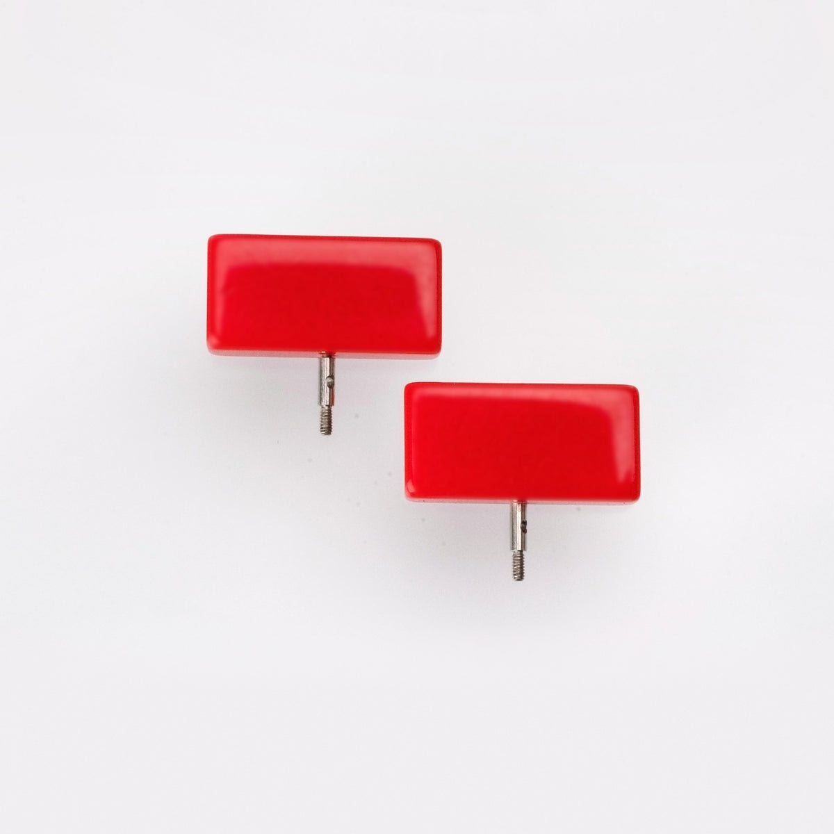 Two red ChiaoGoo Mini [M] end stoppers on a light gray background. Each rectangular stopper has a thin threaded metal post on its bottom edge.