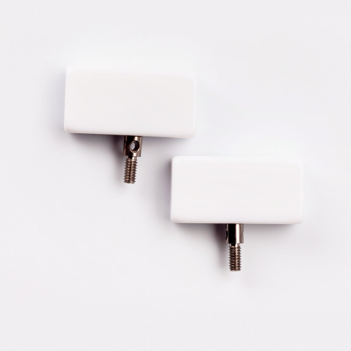 Two white ChiaoGoo Small [S] end stoppers on a light gray background. Each rectangular stopper has a threaded metal post on its bottom edge, with a small hole in the post's collar.