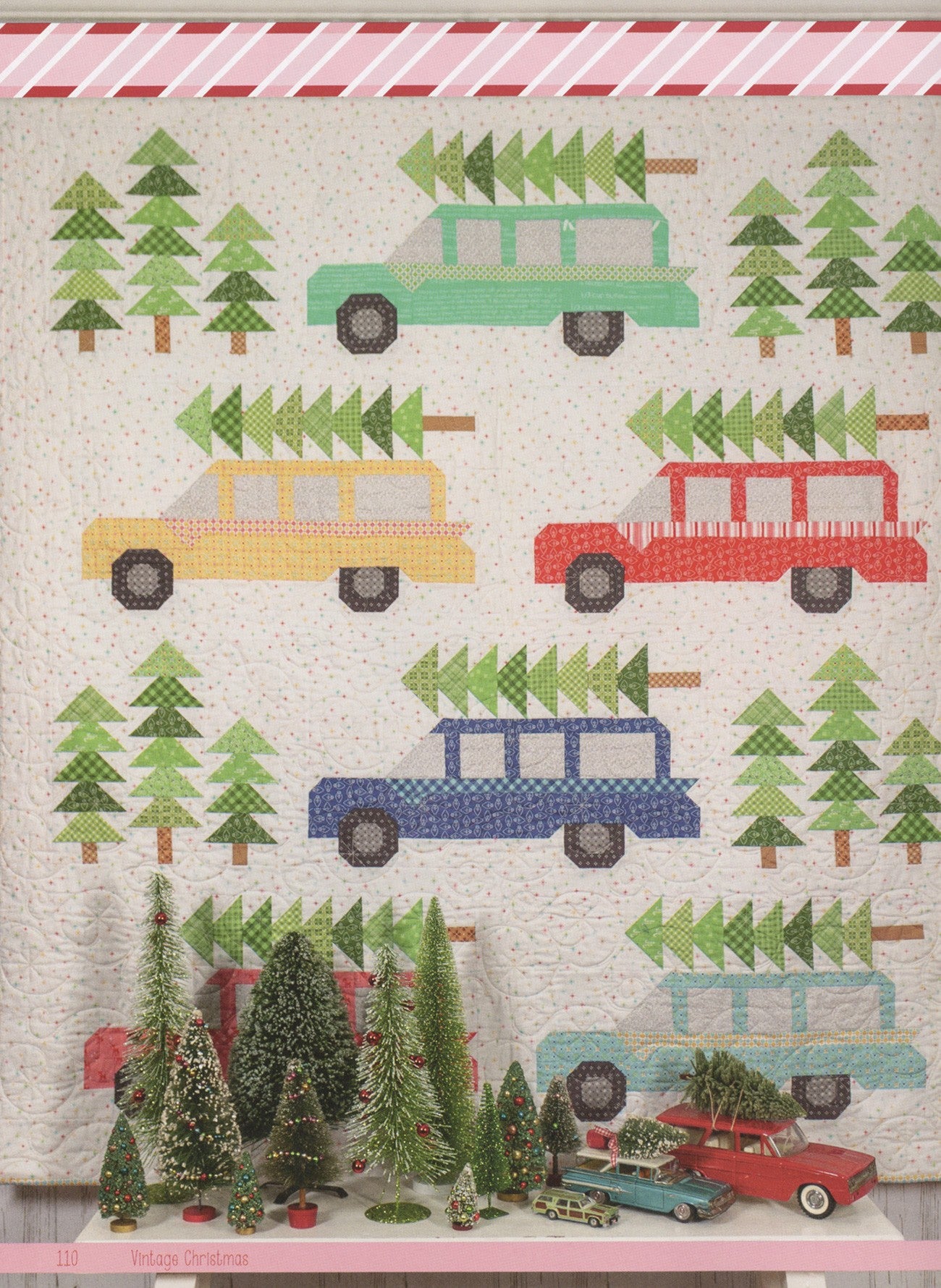 Bringing Home the Christmas Tree Quilt from Vintage Christmas by Lori Holt for It's Sew Emma, with pieced station wagons in mint, yellow, red, blue, and aqua carrying Christmas trees among pieced pine trees, styled with bottlebrush trees and vintage toy cars.
