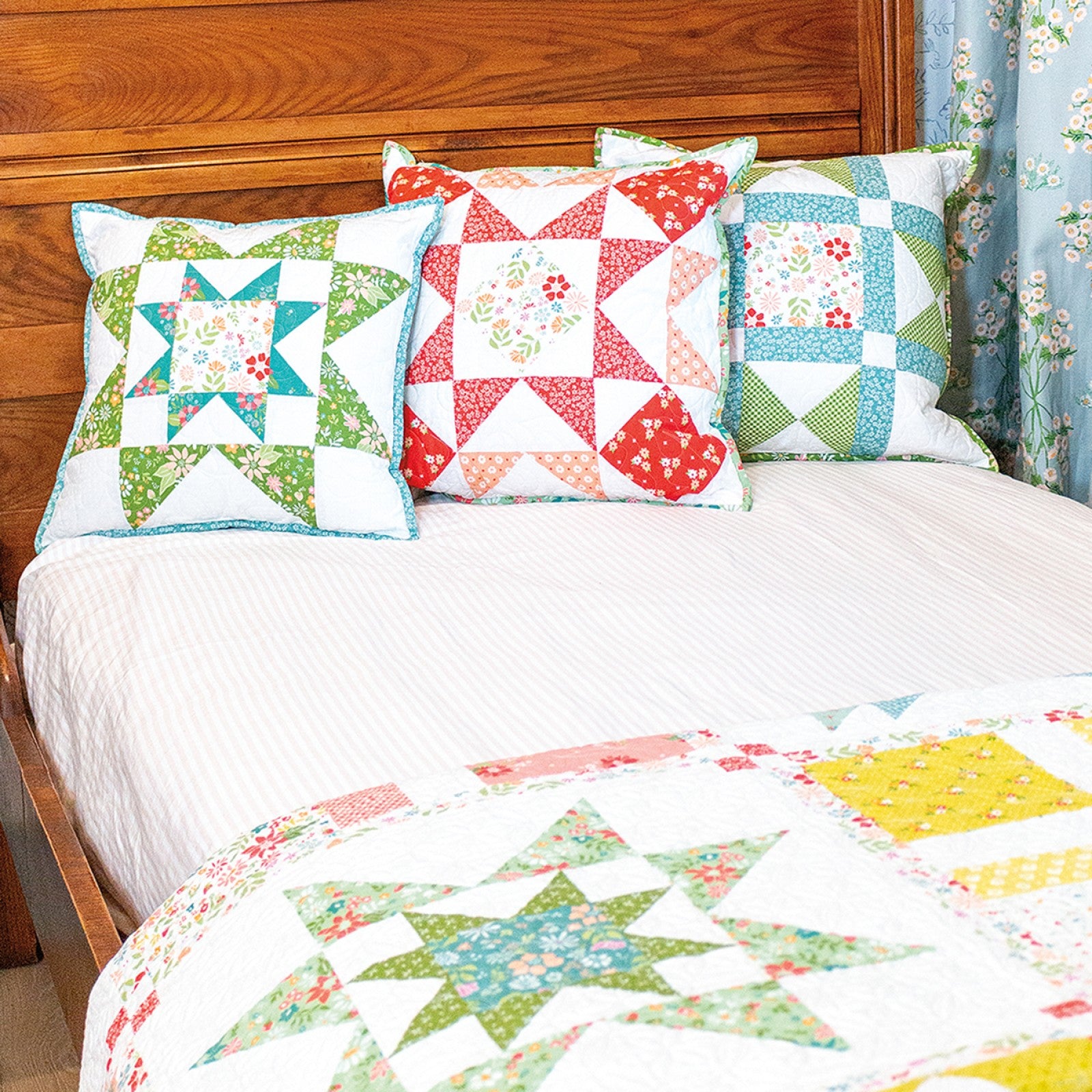 Three Family Favorites block pillows on a bed with a star sampler quilt.