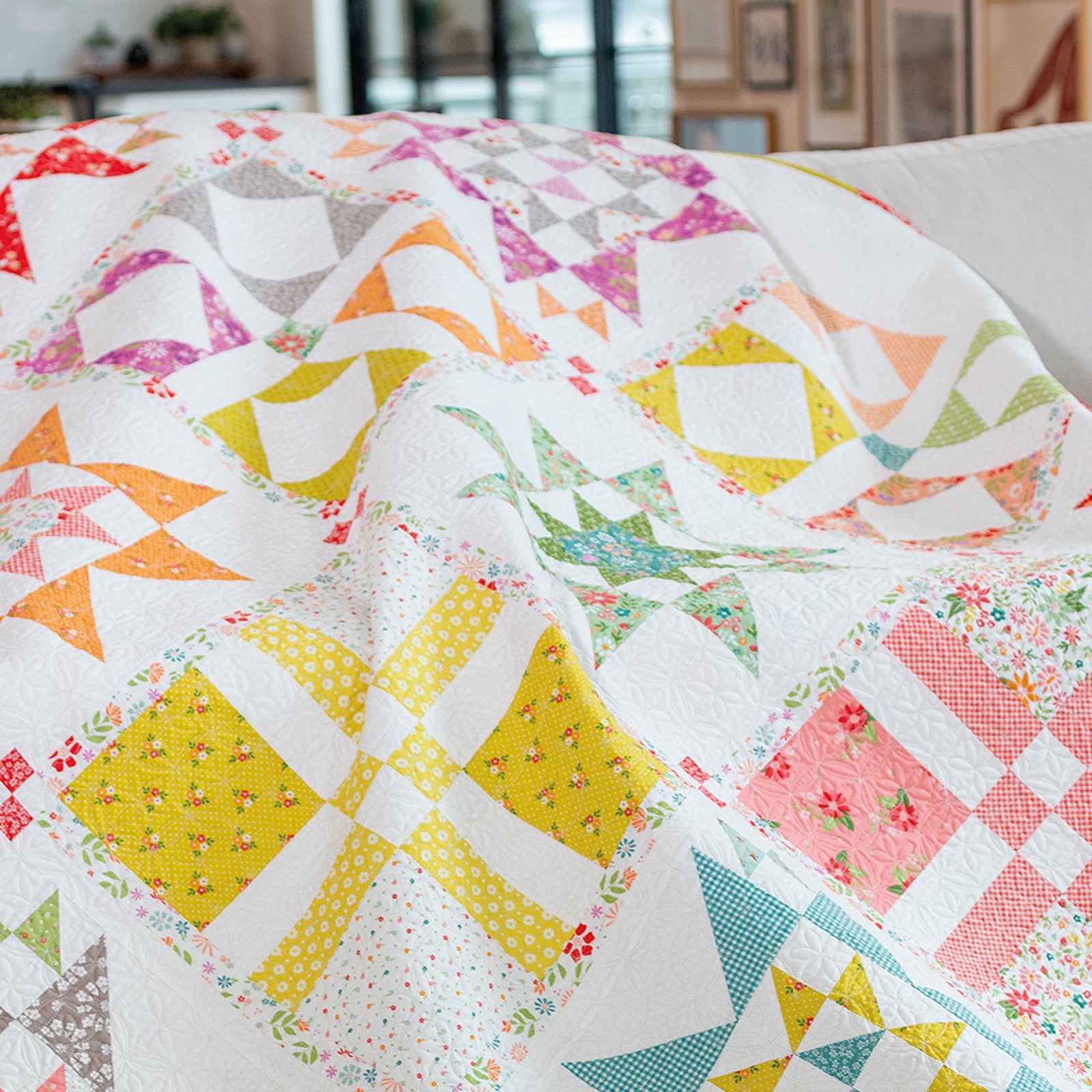 Close-up of a Family Favorites sampler quilt showing pieced blocks in yellow, pink, and green.