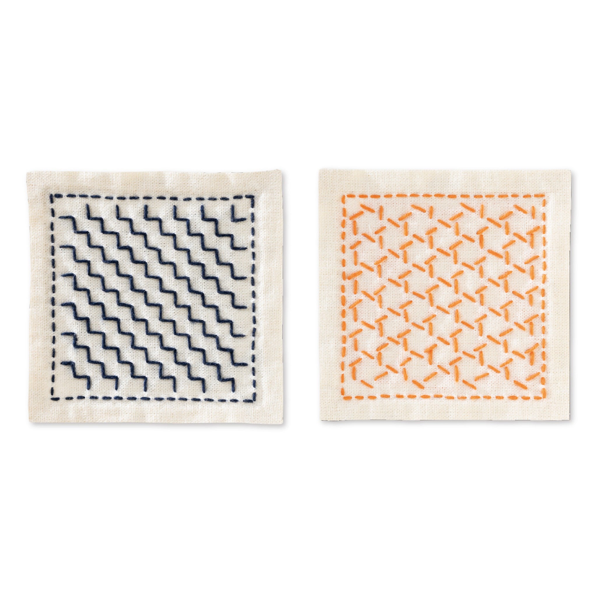 Two finished coasters from the Olympus hitomezashi sashiko coaster kit SK-0482 from EmmaCreation on natural unbleached ecru cotton: the dan-tsunagi linked steps design stitched in deep navy diagonal staircase lines on the left and the kagome basket weave design stitched in orange on the right, each framed by a dashed running-stitch border.